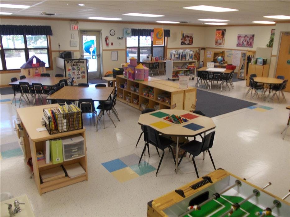Classroom with multiple tables and chairs, storage units, and a foosball table