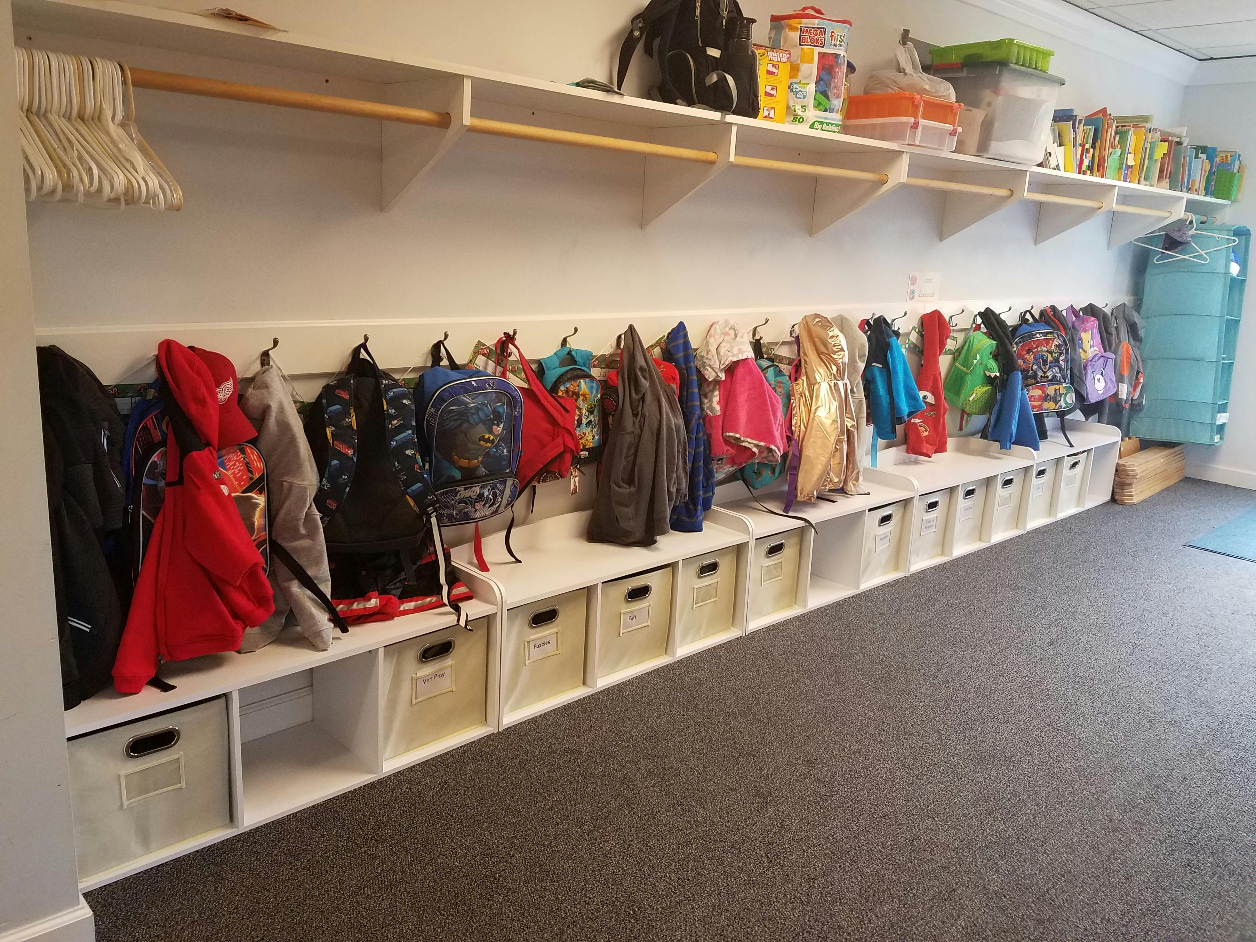 Coats and backpacks hanging on hooks above storage cubbies