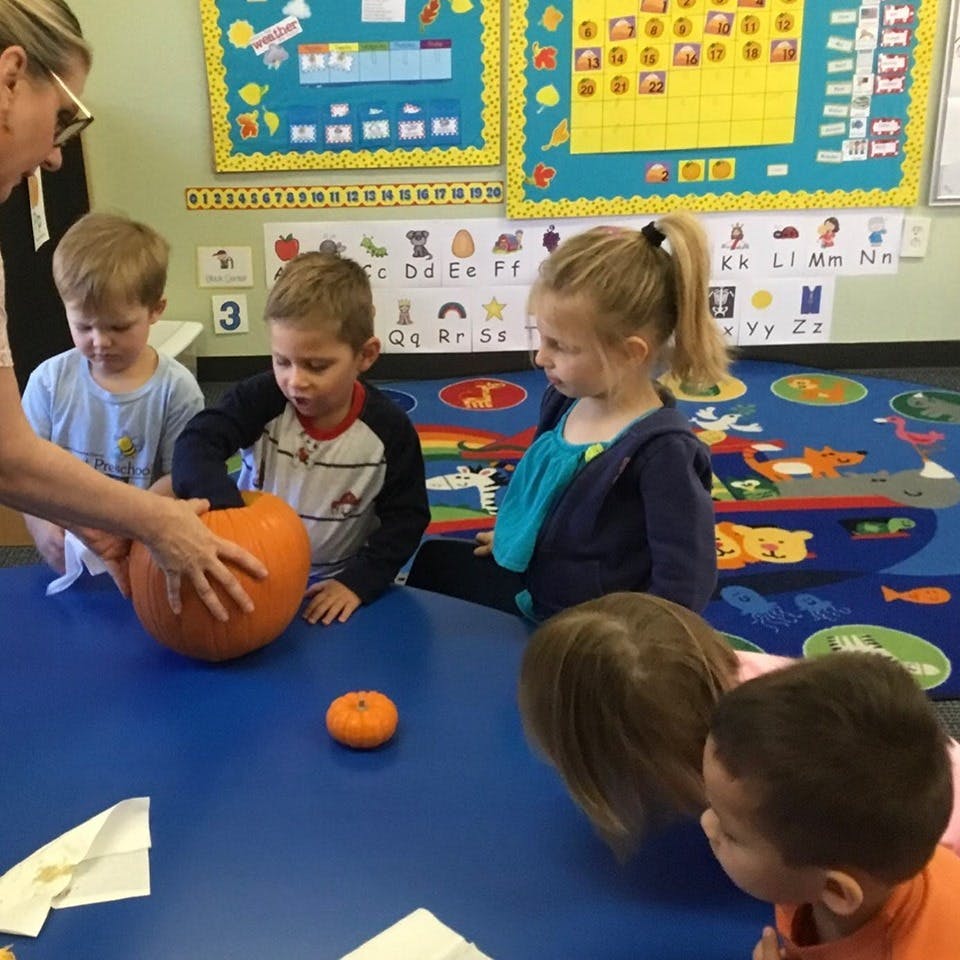 Adult and children gathered around a pumpkin on a table