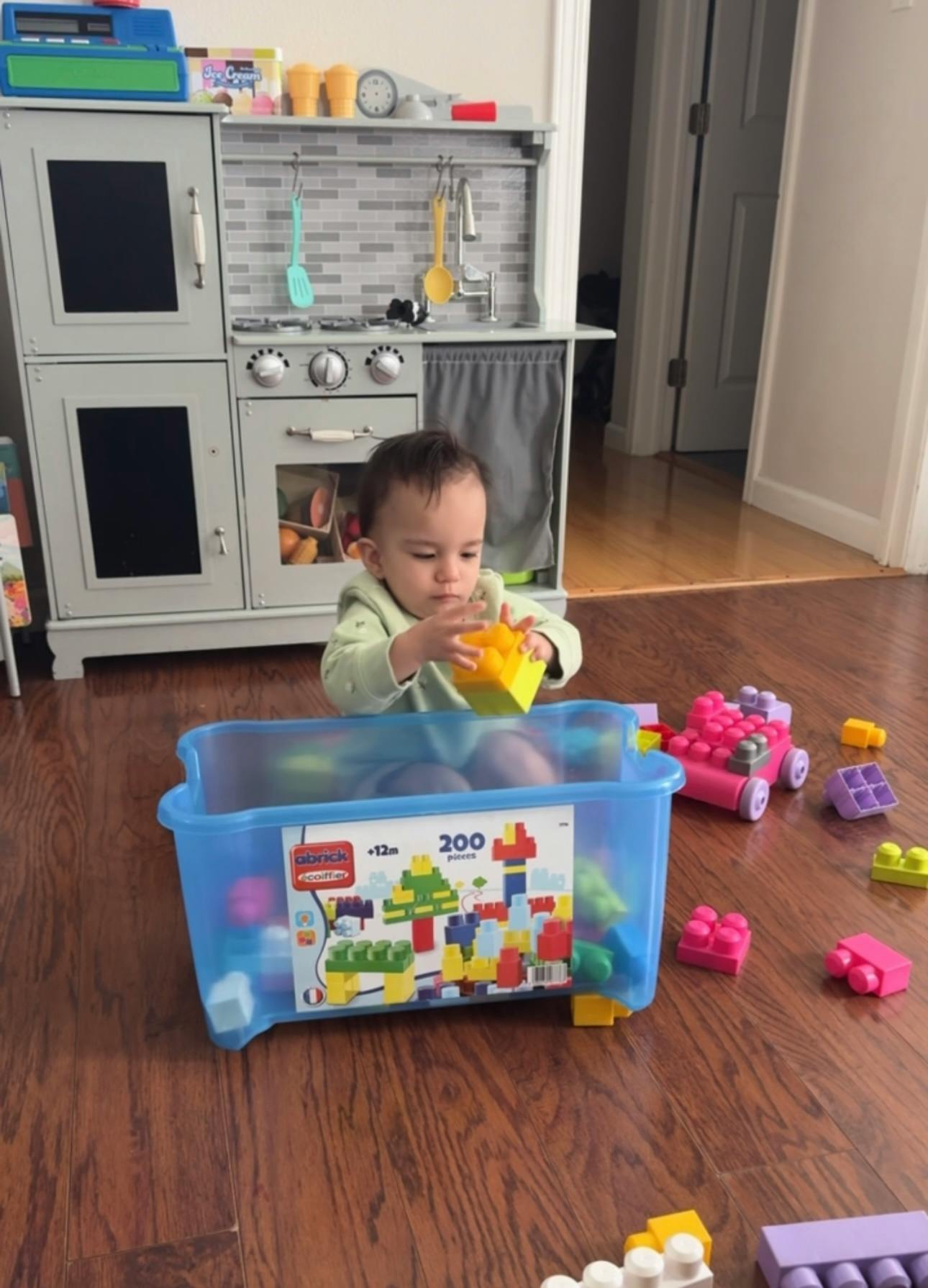 Child playing with large building blocks on a wooden floor