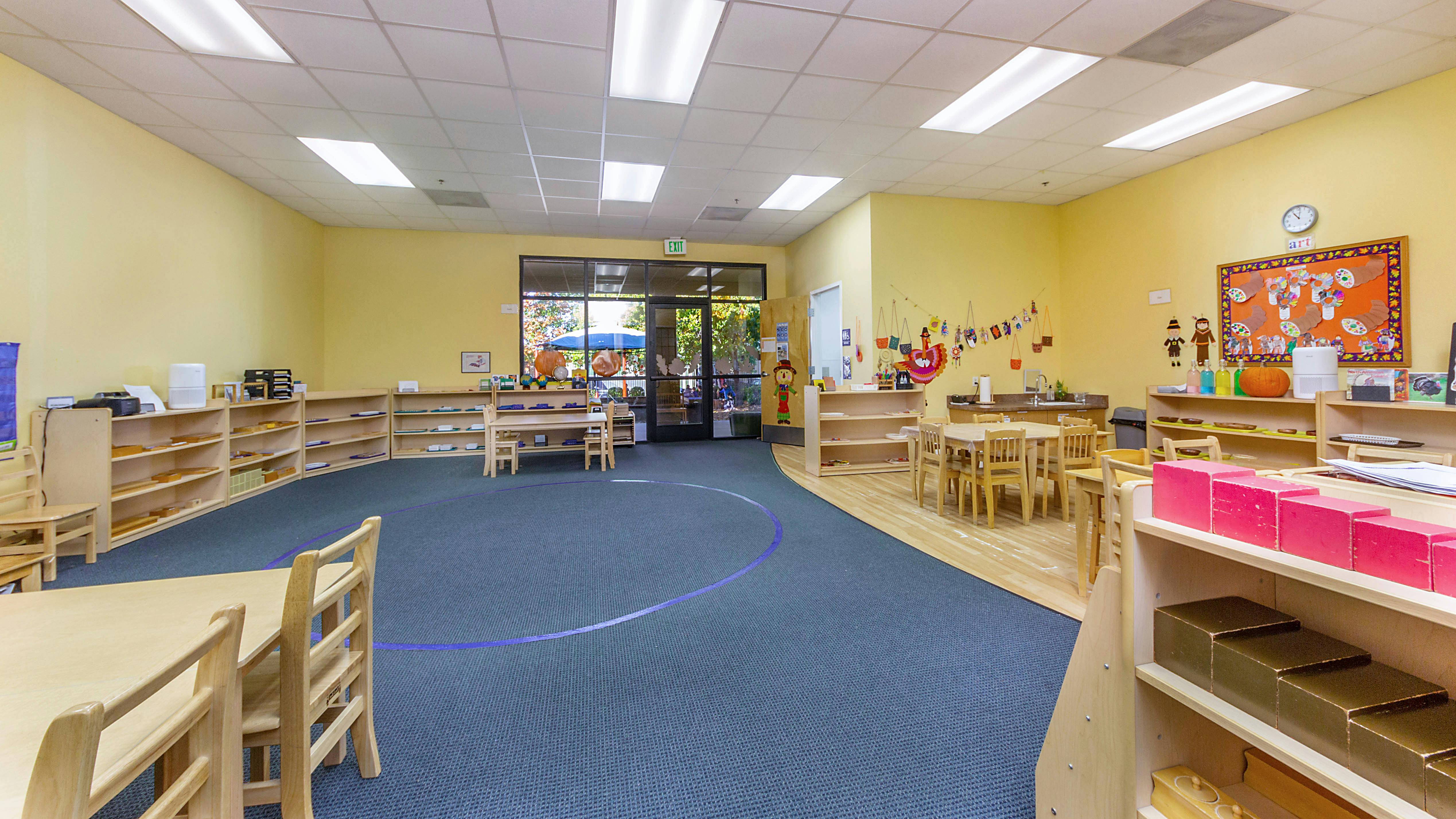 Empty classroom with blue carpet and wooden shelves