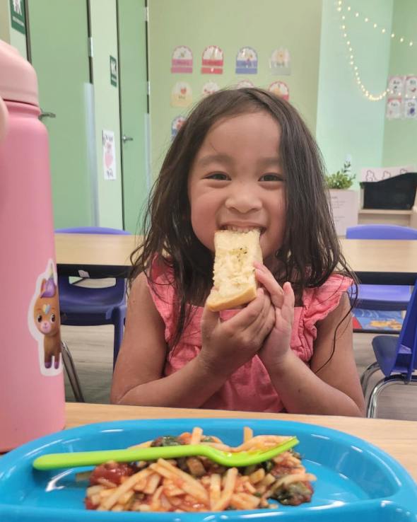 Child eating a slice of bread in a classroom
