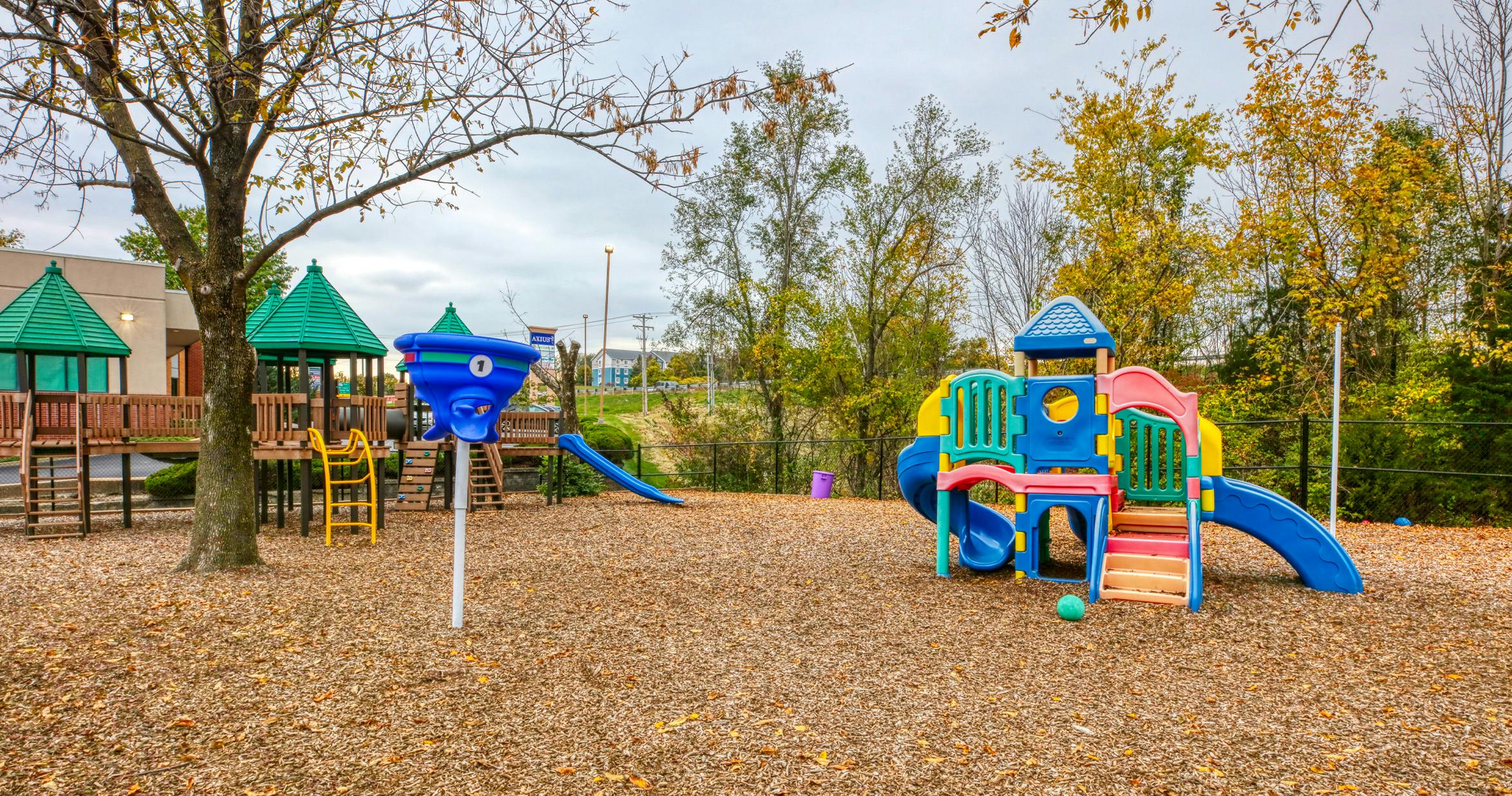 Colorful playground equipment and wooden play structures on a wood chip ground
