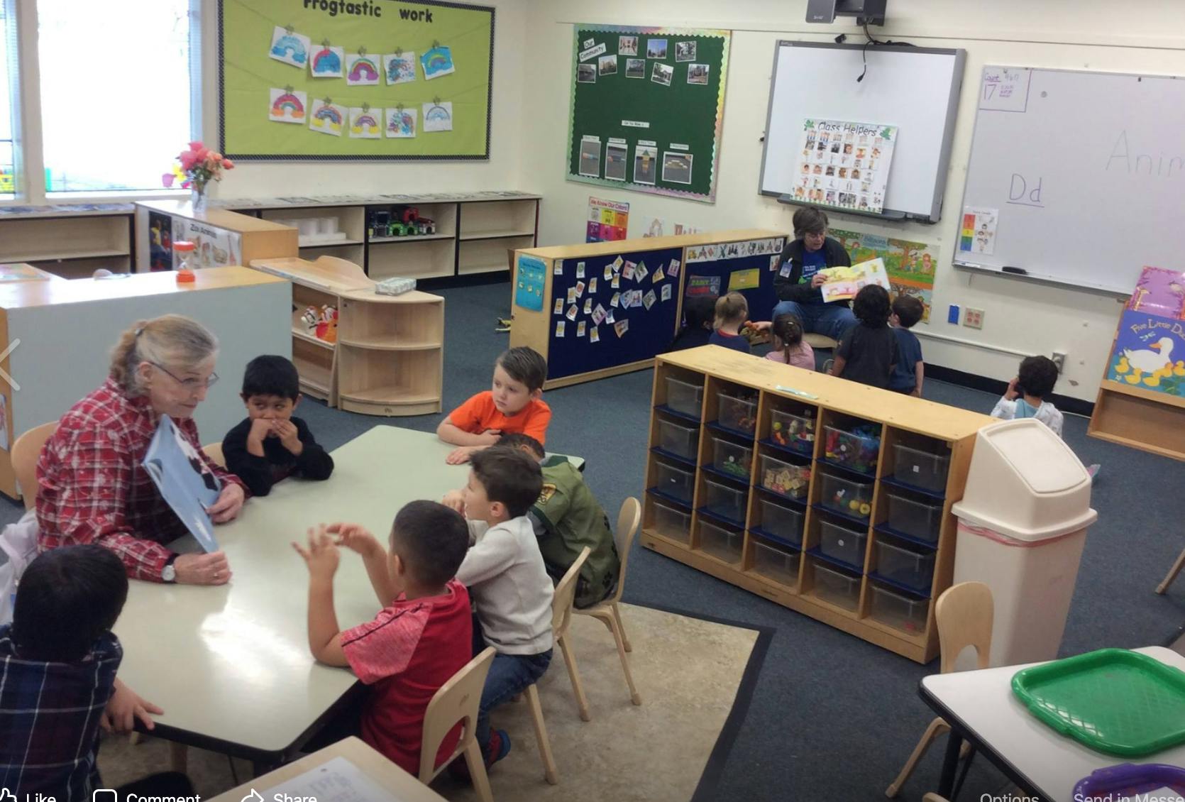 Adult reading to children at a table in a classroom