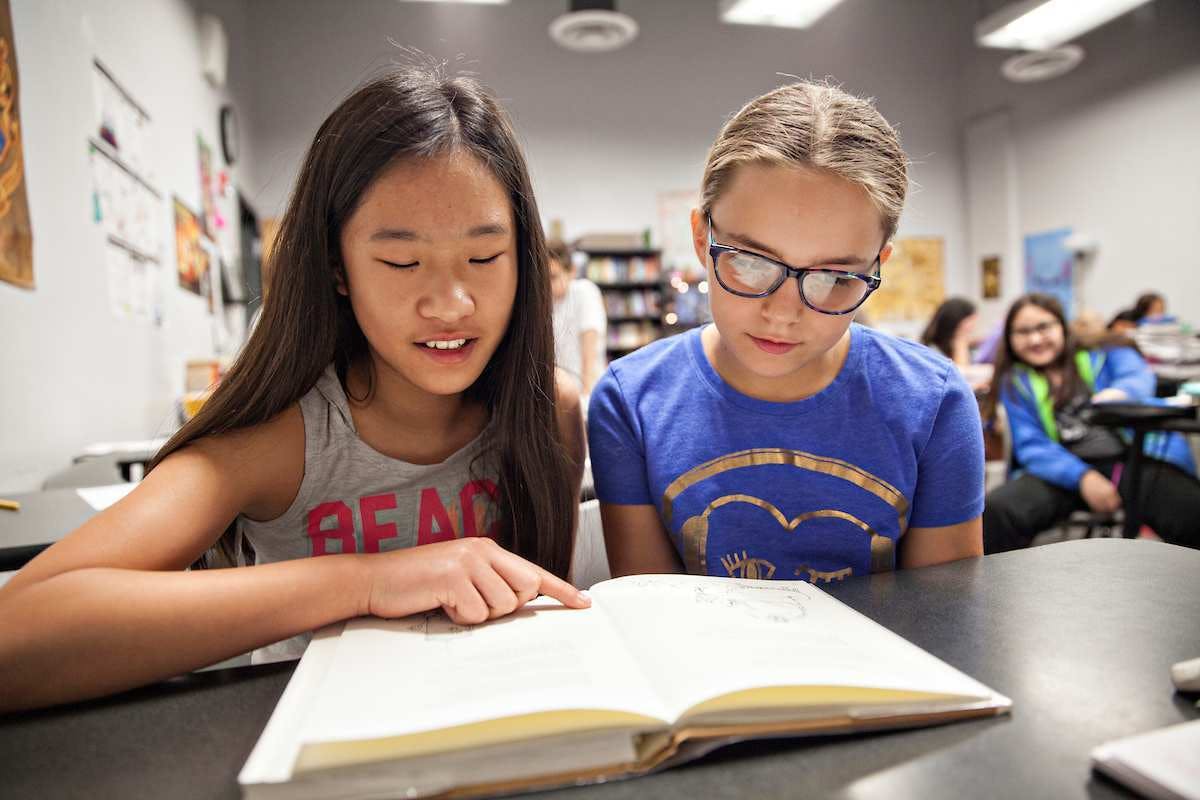 Two children reading a book together in a classroom