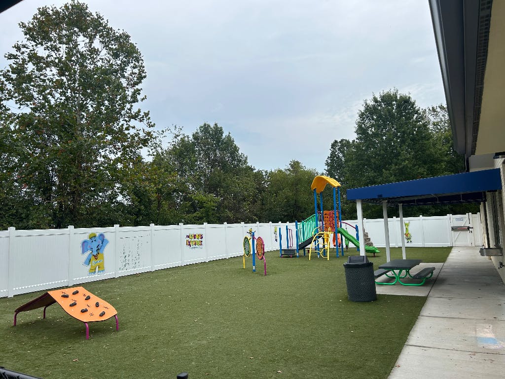 Outdoor playground with artificial turf, climbing structures, and slides