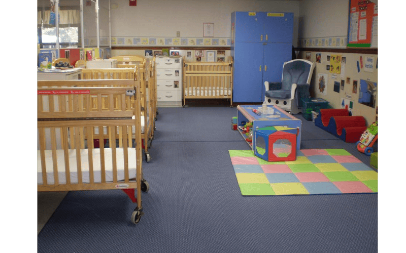 Cribs and colorful play area in a daycare or nursery room