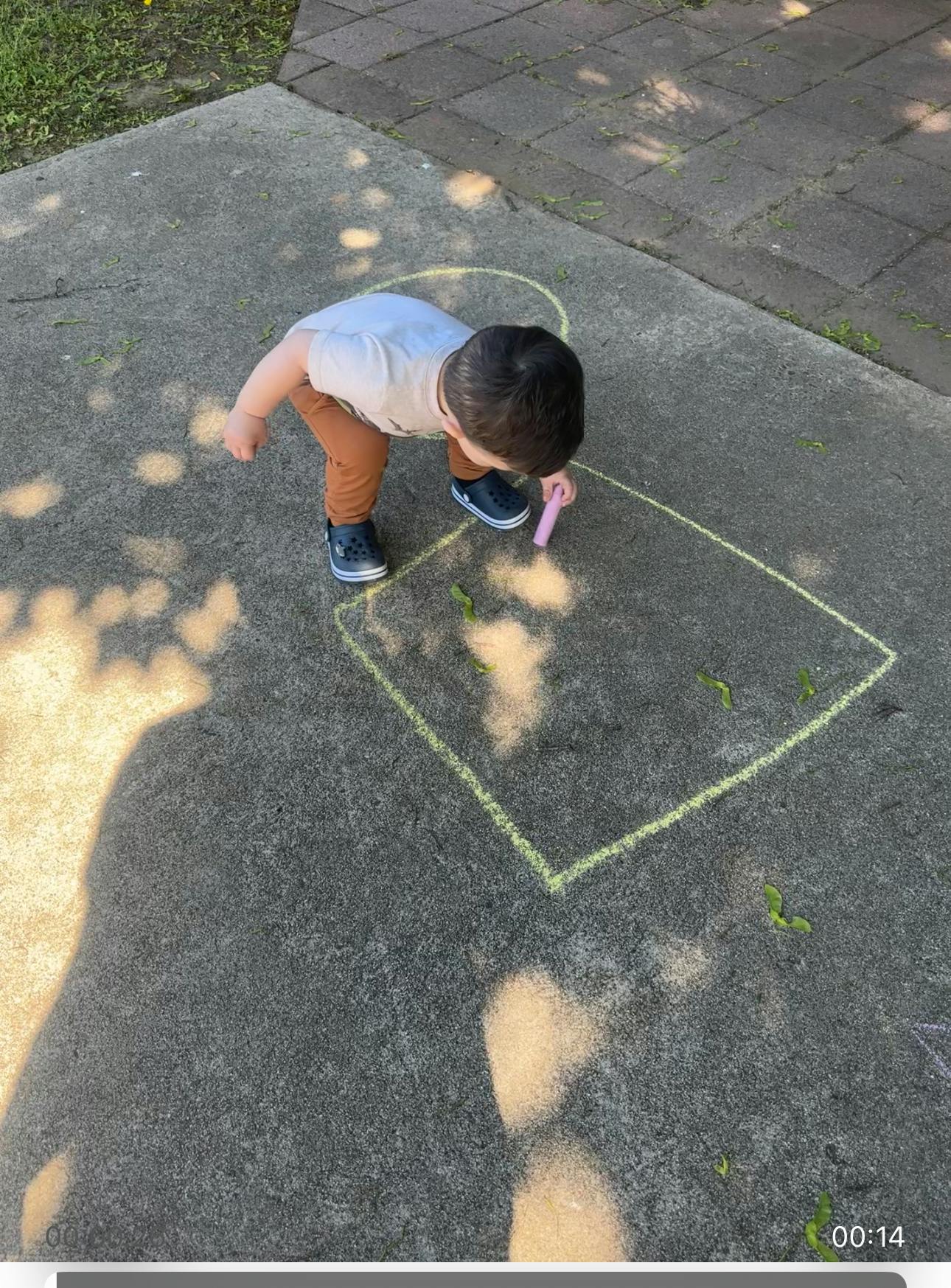 Child drawing with chalk on pavement