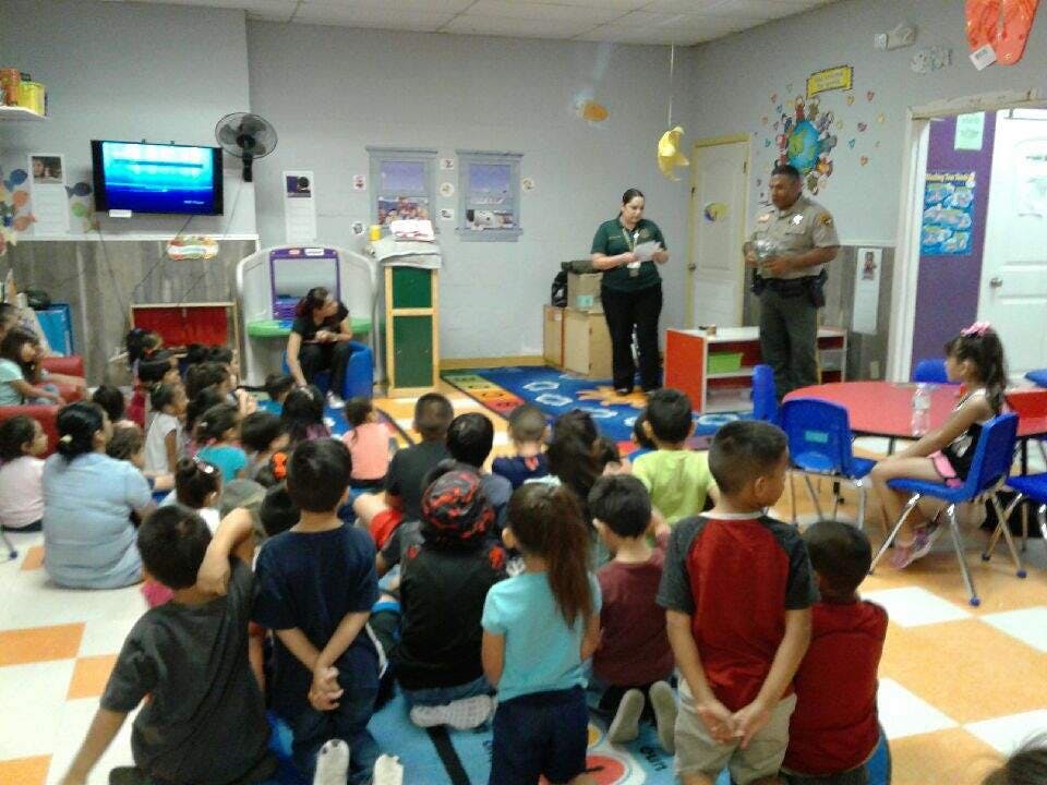 Adults speaking to a group of children in a classroom