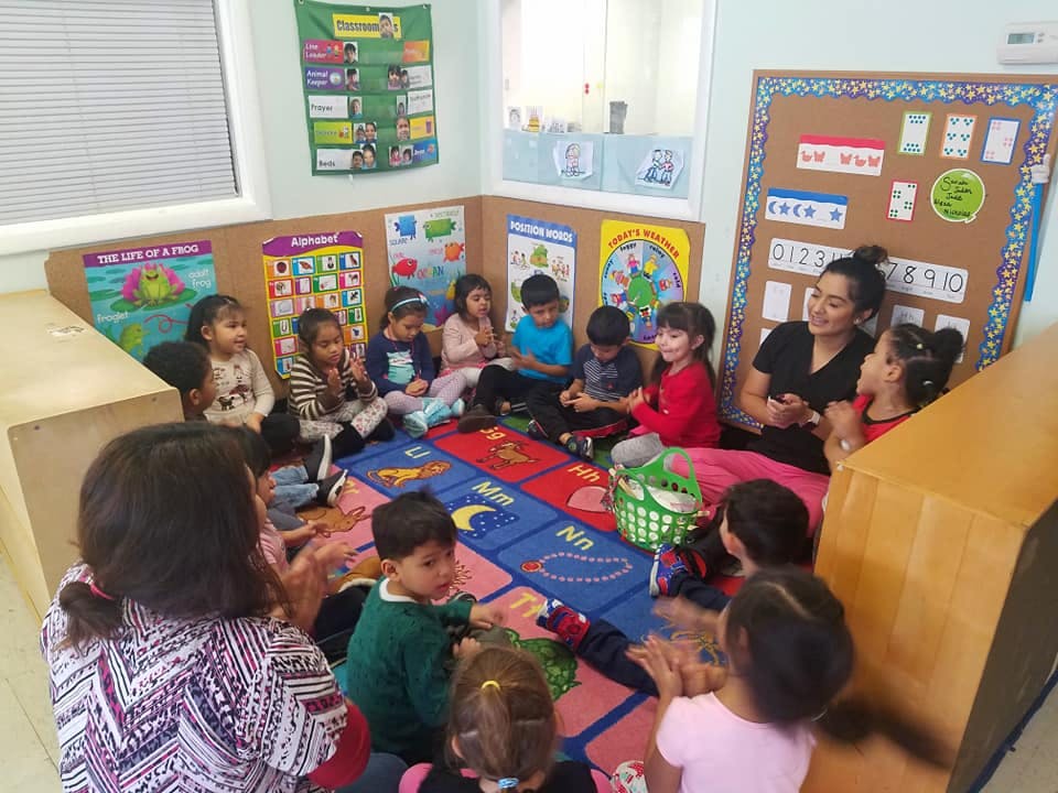 Adults and children sitting on a rug in a classroom