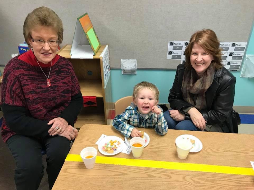 Two people and a child sitting at a table with drinks and snacks