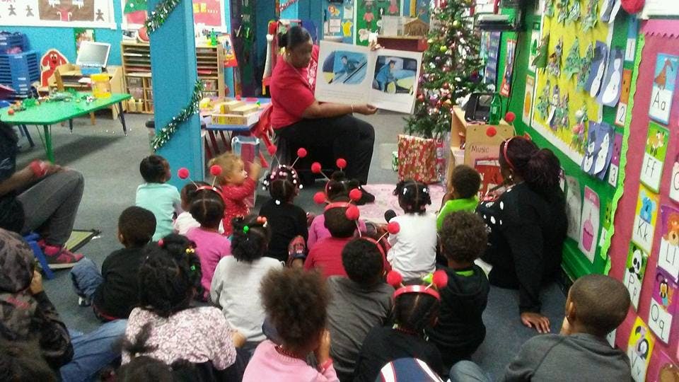 Person reading a book to a group of children in a classroom