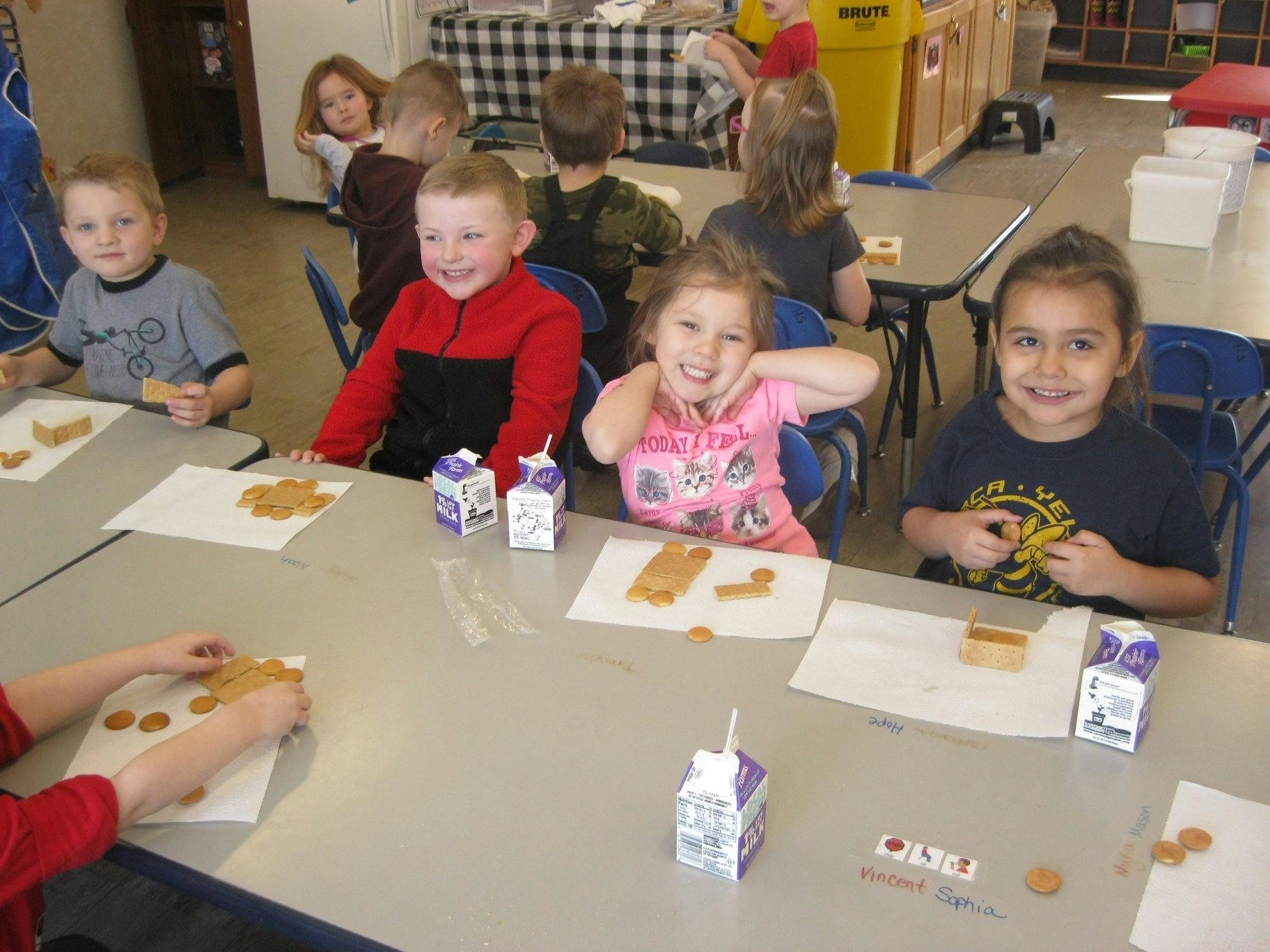 Children sitting at tables with snacks and milk cartons