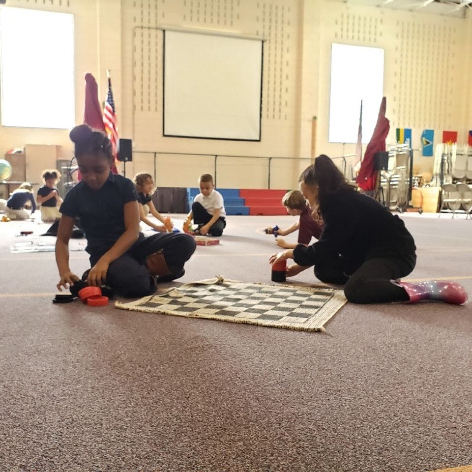 Children playing on the floor with a chessboard and other items
