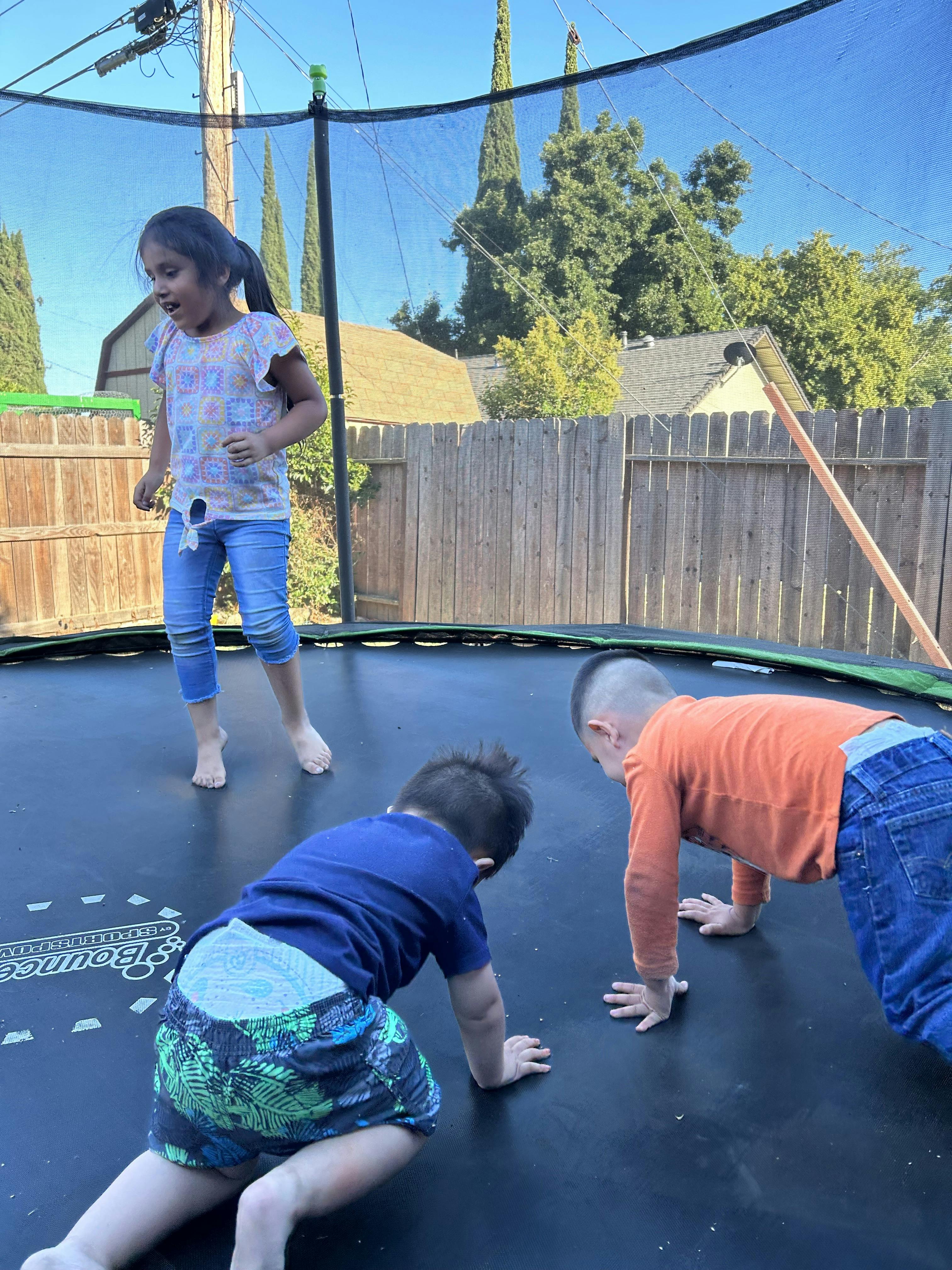 Three children playing on a trampoline