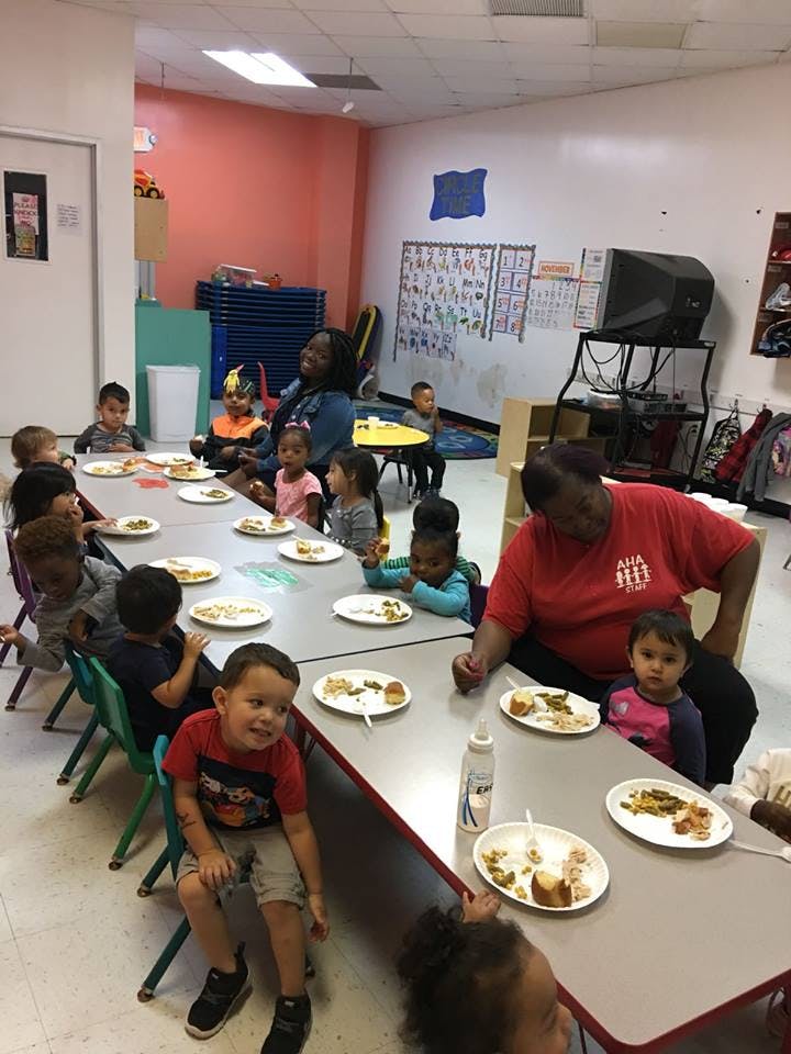 Adults and children eating at tables in a classroom