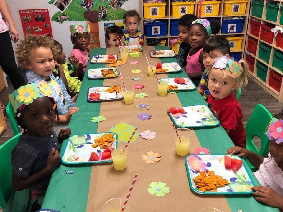 Children sitting at a long table with plates of food and drinks