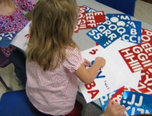 Child working with alphabet letter cutouts on a table