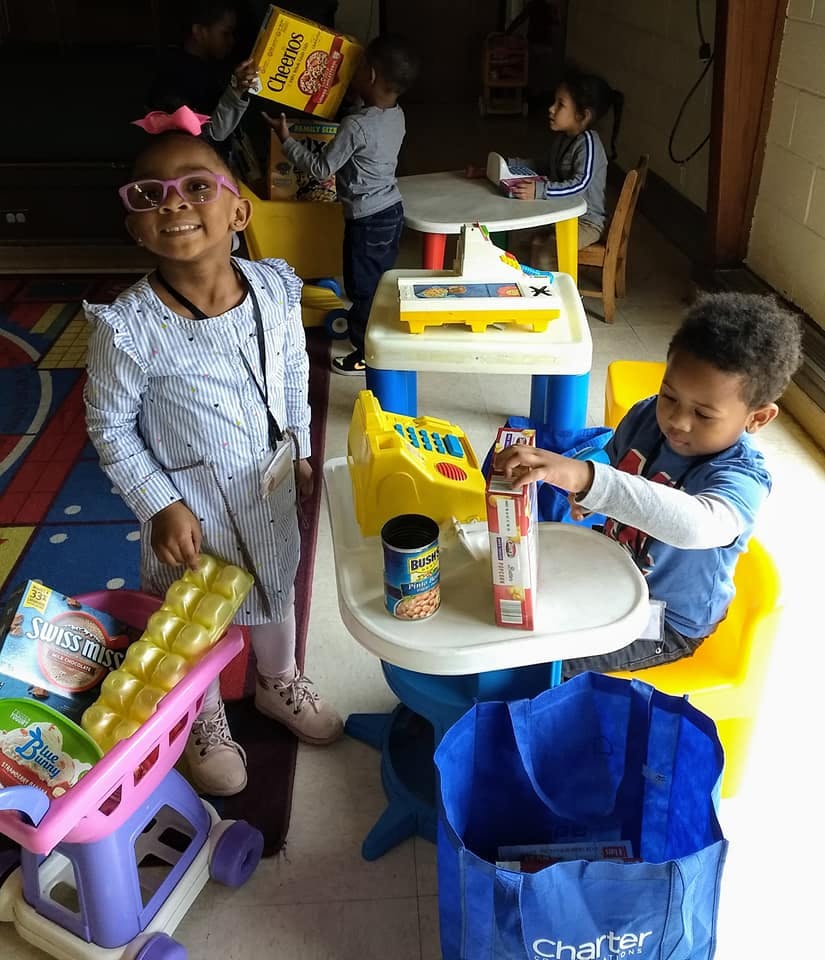 Children playing with toy groceries and a toy cash register
