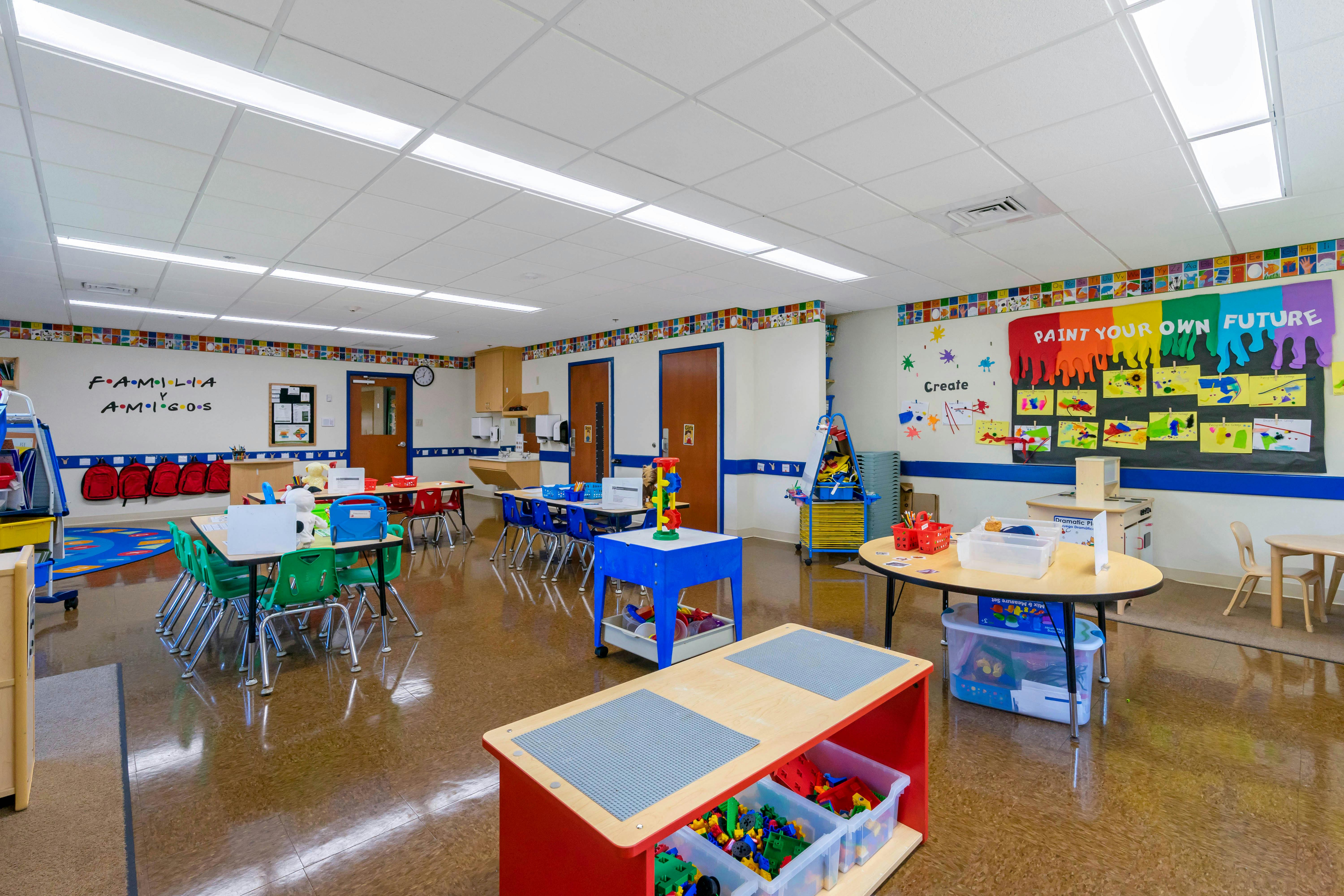 An empty classroom with colorful walls and several small tables and chairs