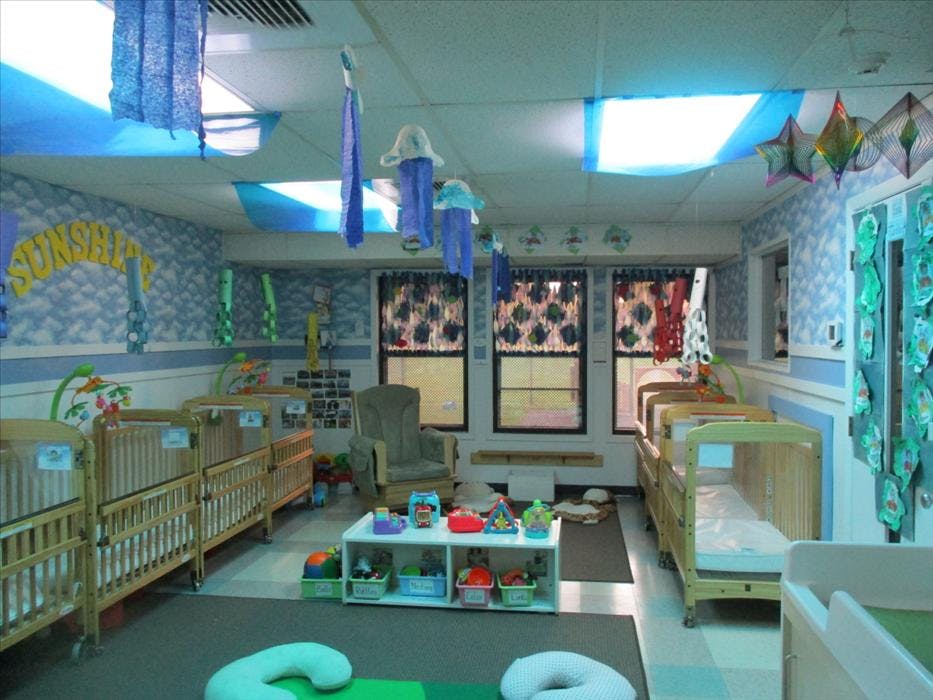 A colorful nursery room with multiple cribs, a rocking chair, and toys