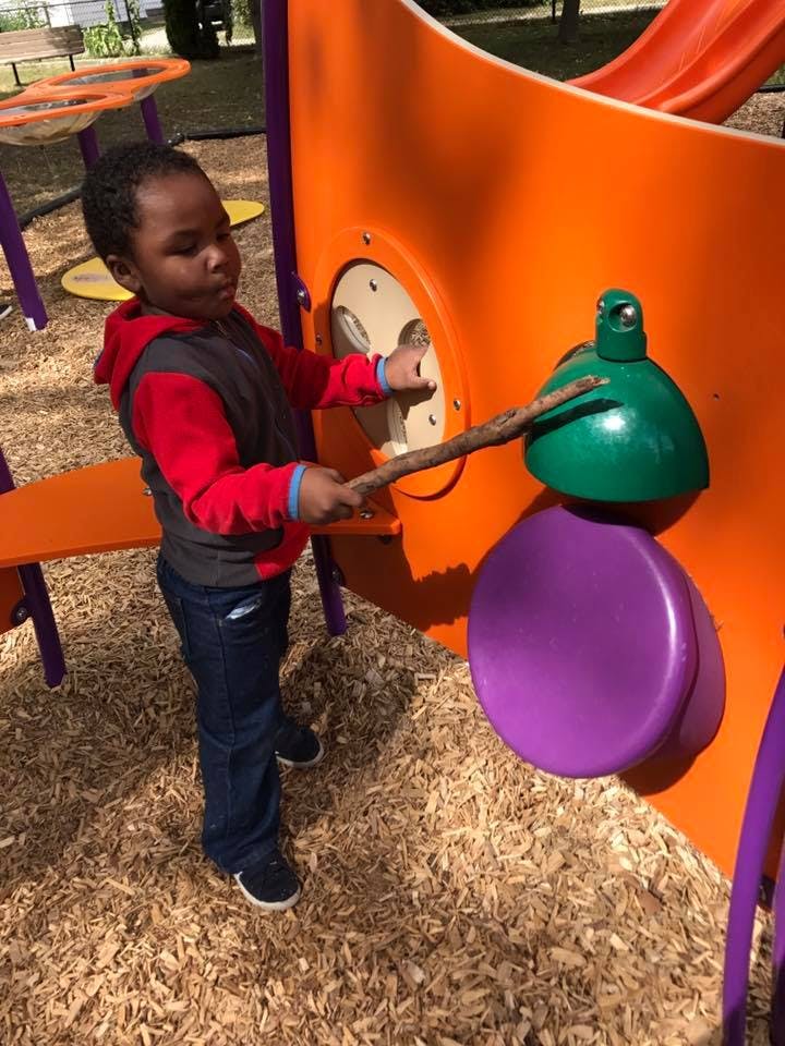 Child playing with a stick on a playground structure