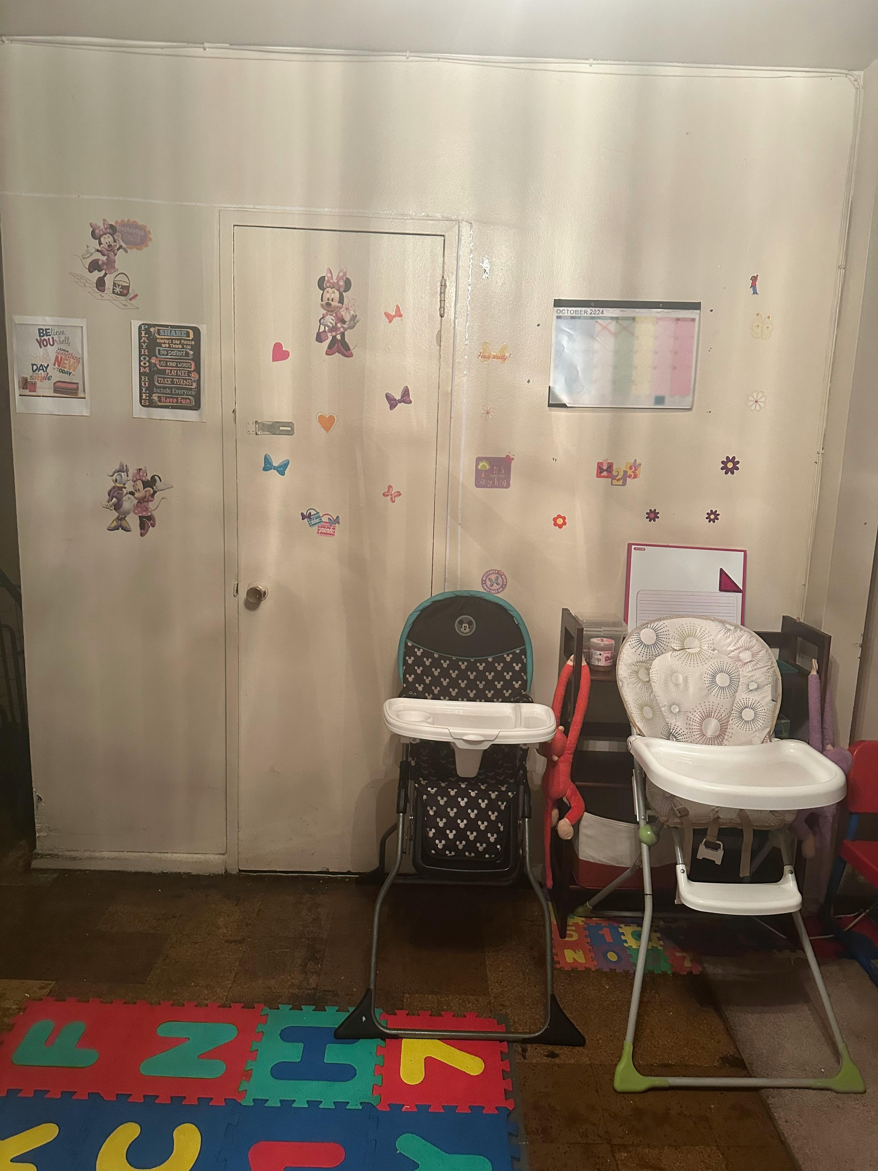 Two high chairs in a room with a playmat on the floor