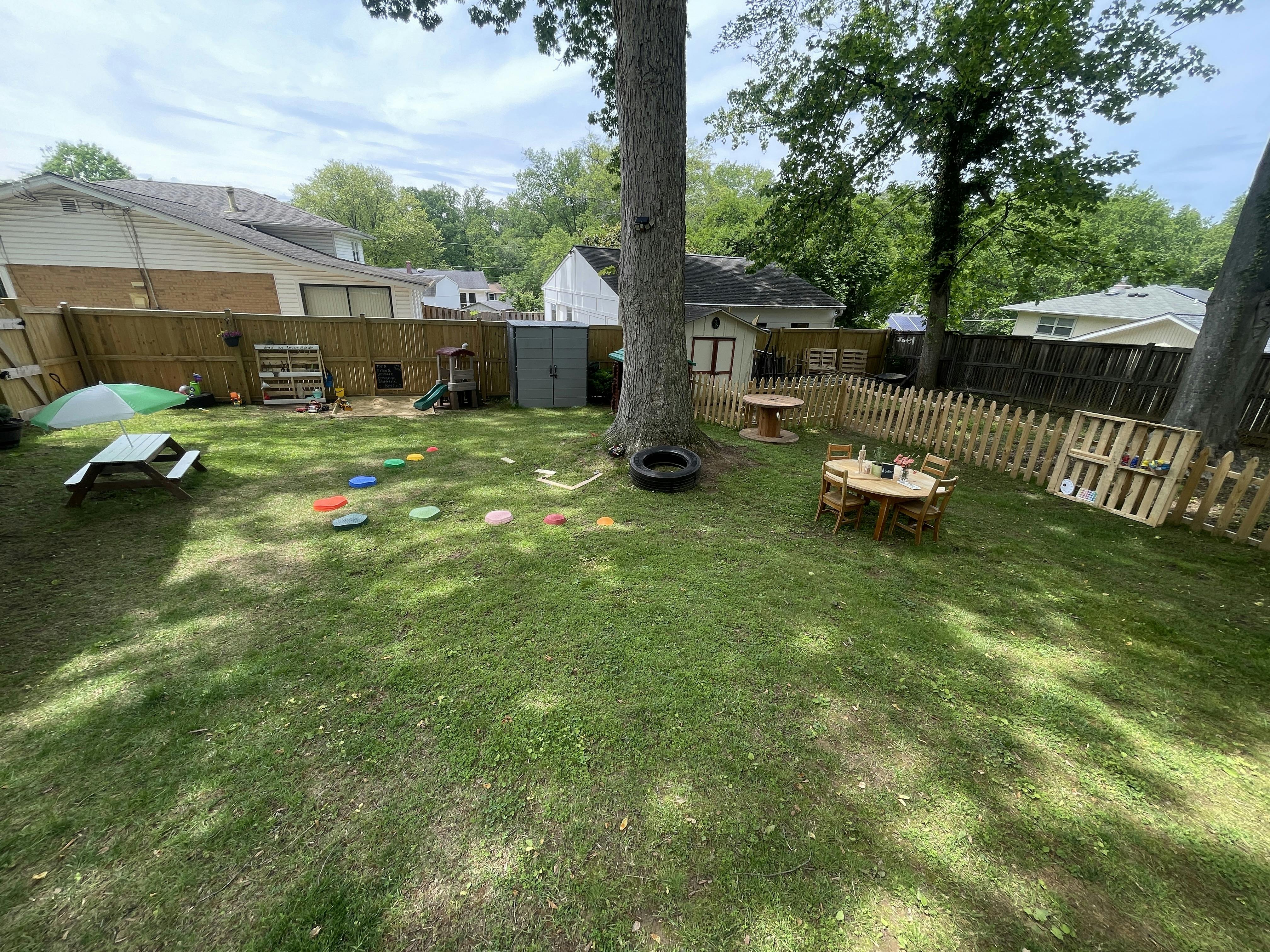 Backyard with a picnic table, small wooden tables, and a wooden fence