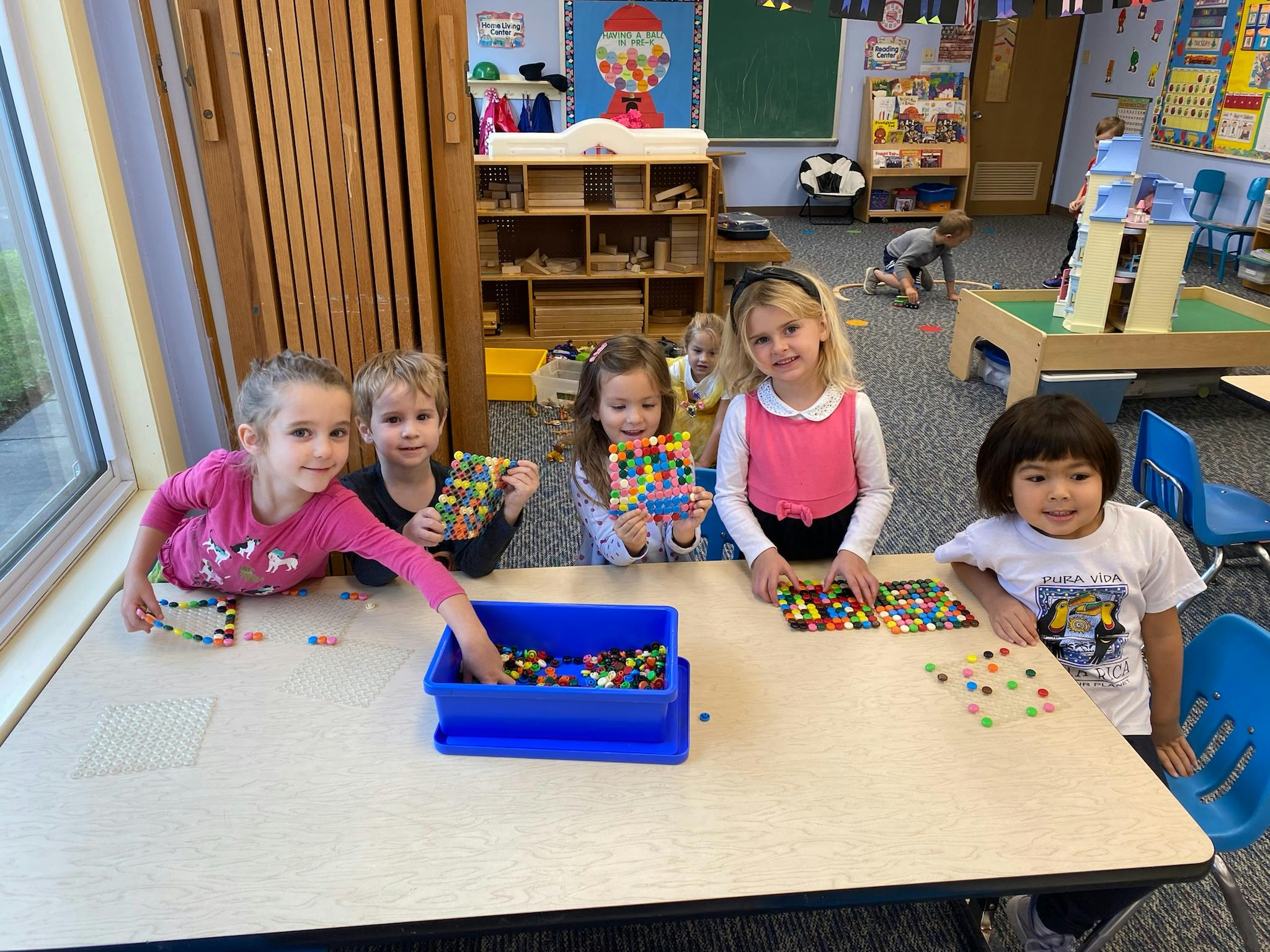Children playing with colorful building blocks at a table in a classroom