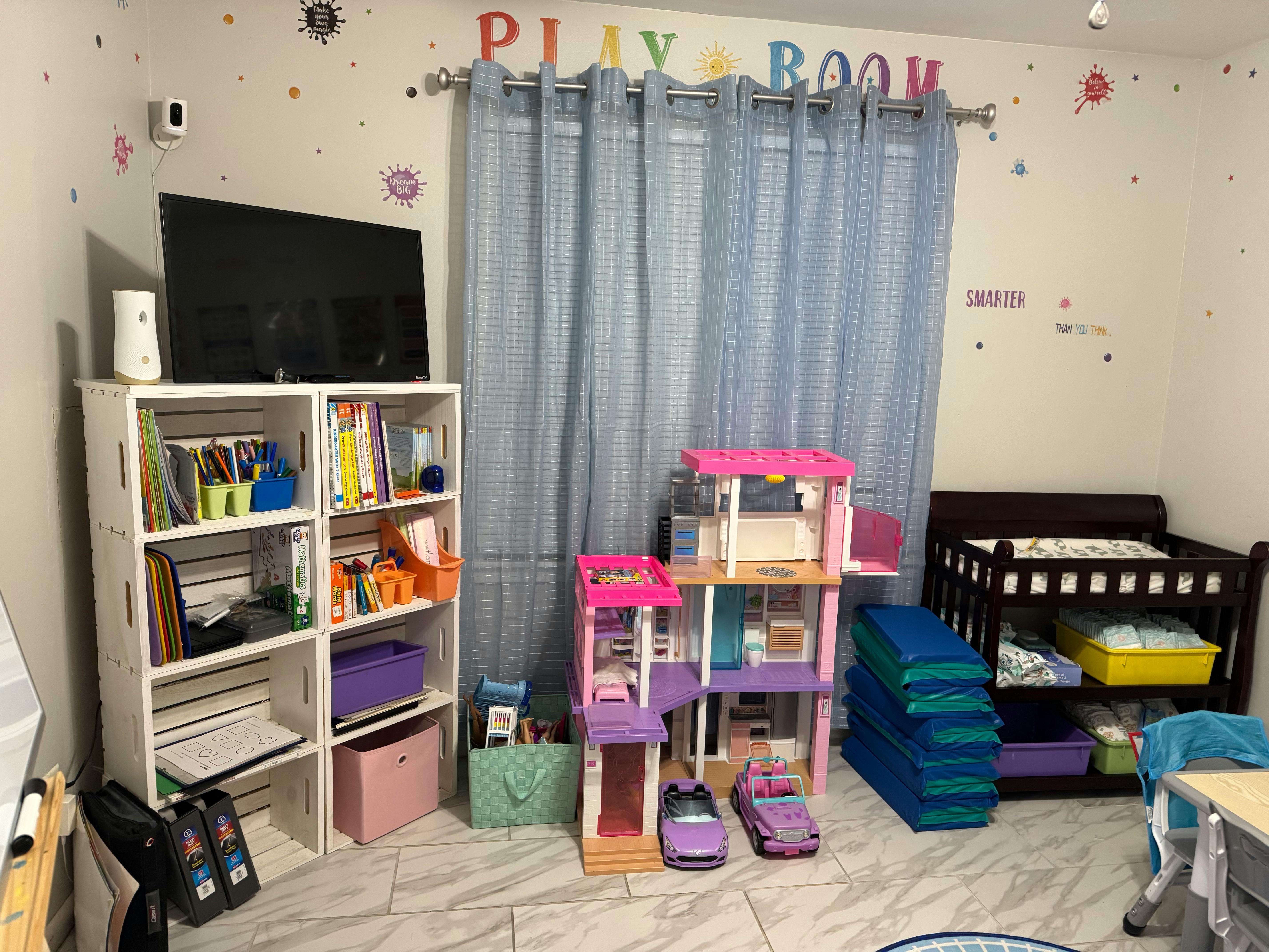 Playroom with a TV, bookshelf, dollhouse, and crib