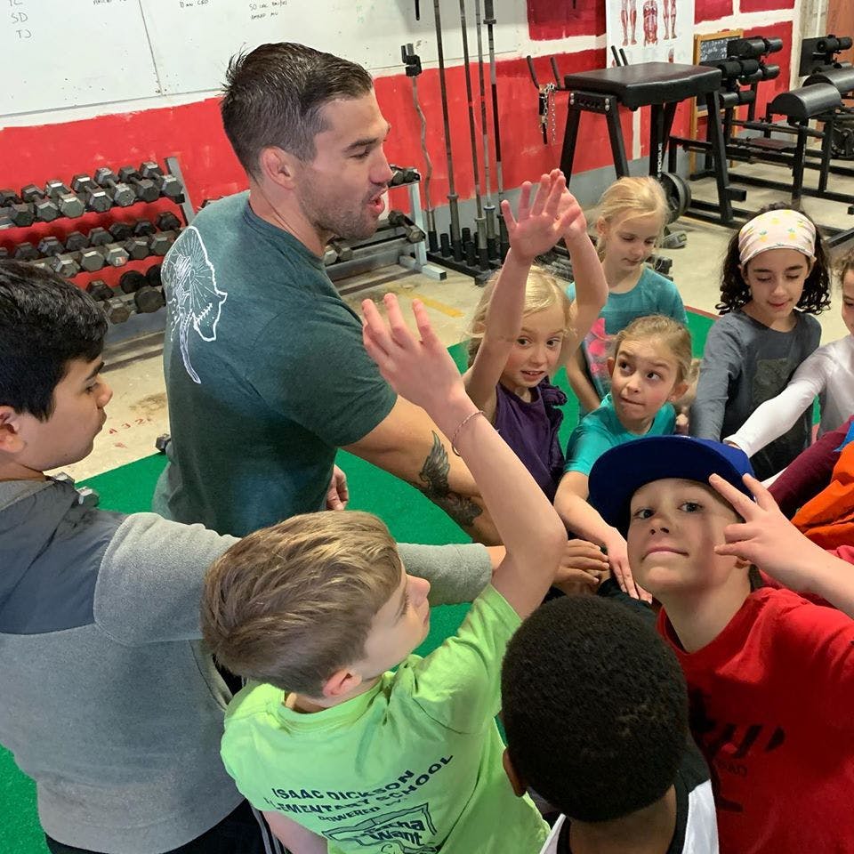 Adult person interacting with a group of children in a gym