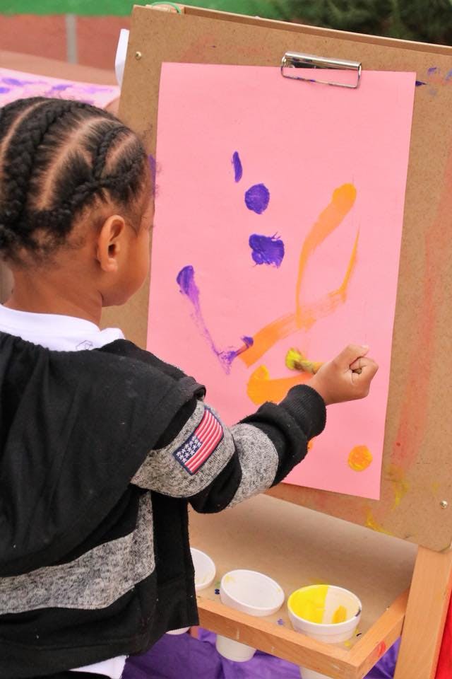 Child painting on an easel with pink paper