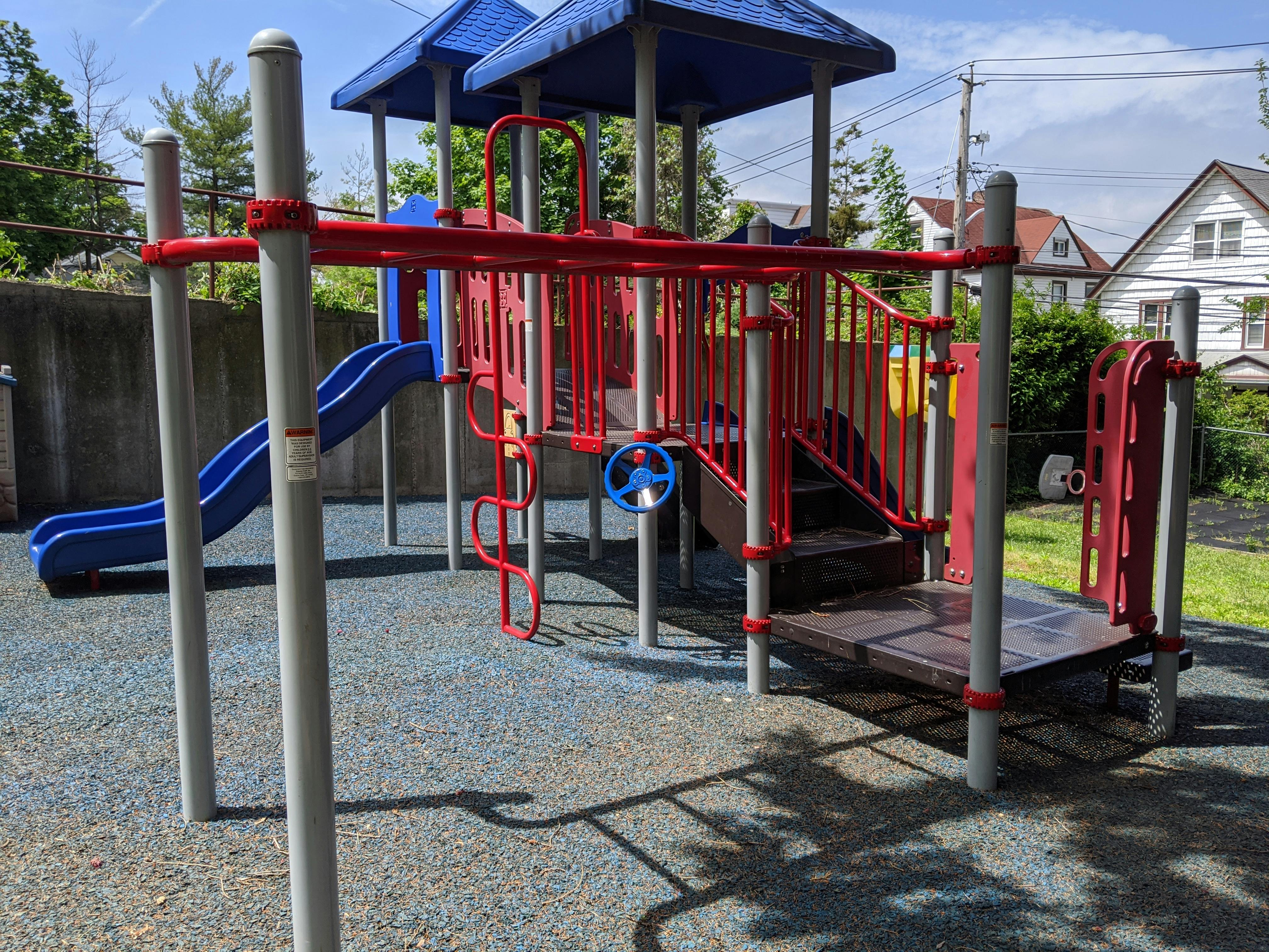 Playground structure with blue slide and red railings