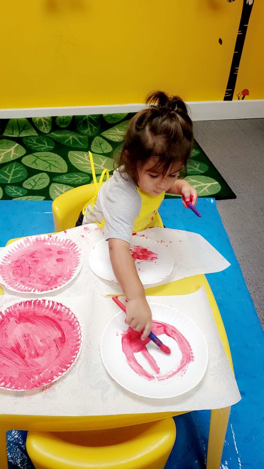 Child painting on paper plates at a table