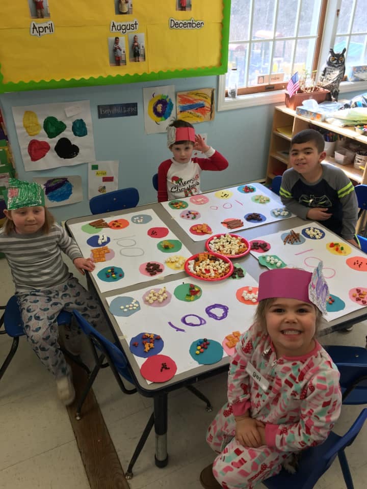 Four children at a table with craft supplies and snacks