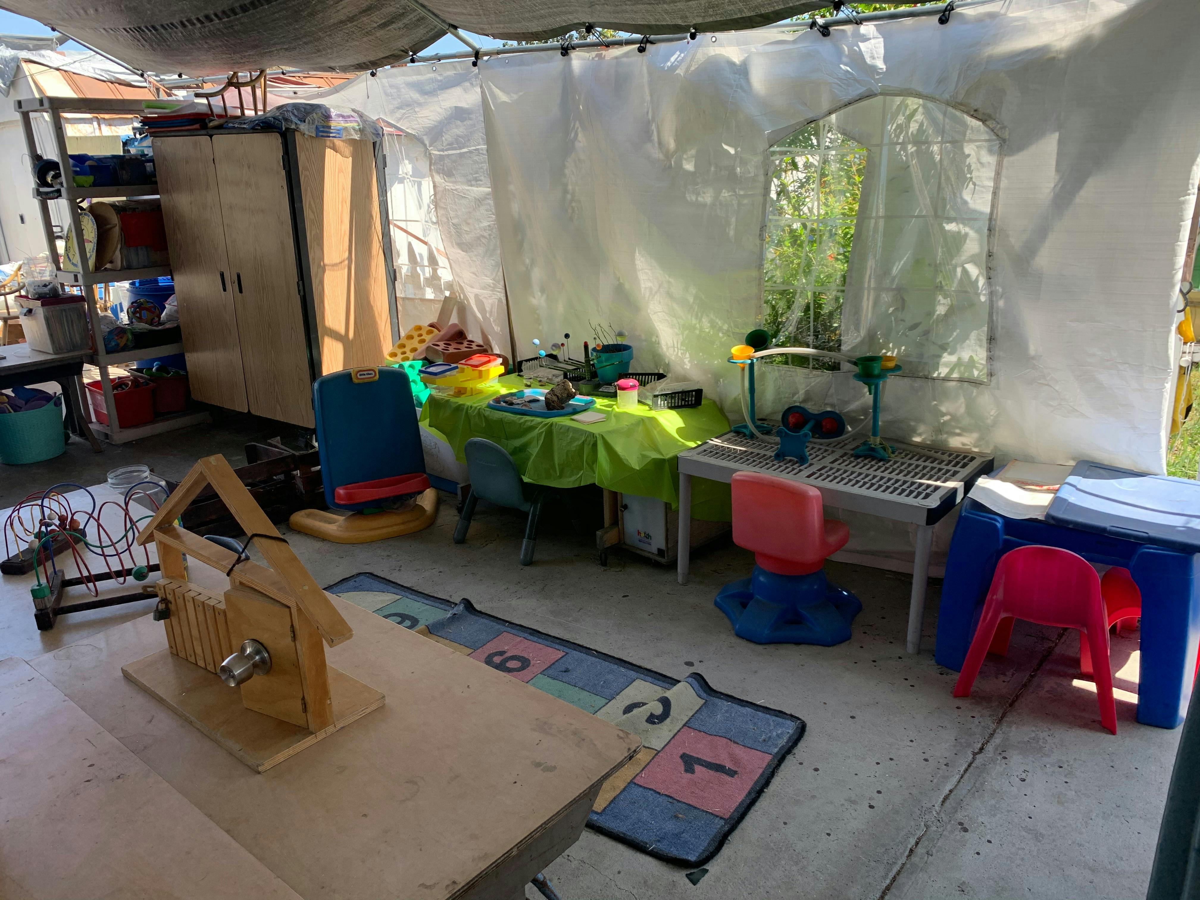 Play area with small tables and chairs under a canopy
