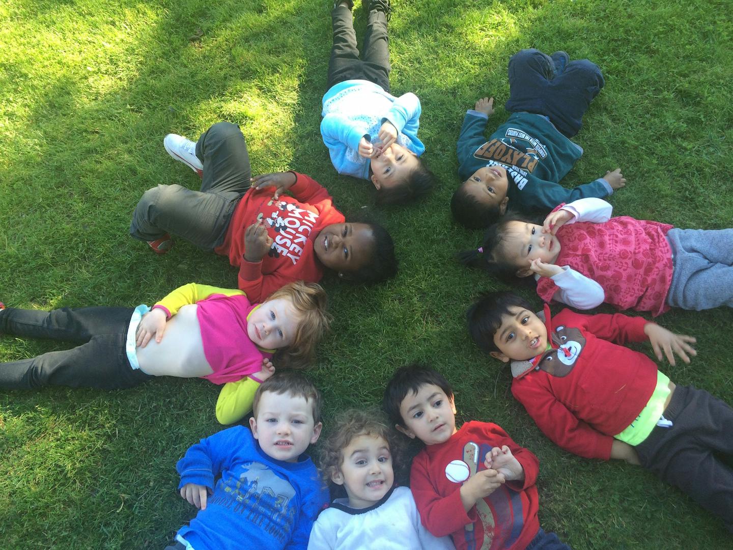 Children lying on grass in a circle