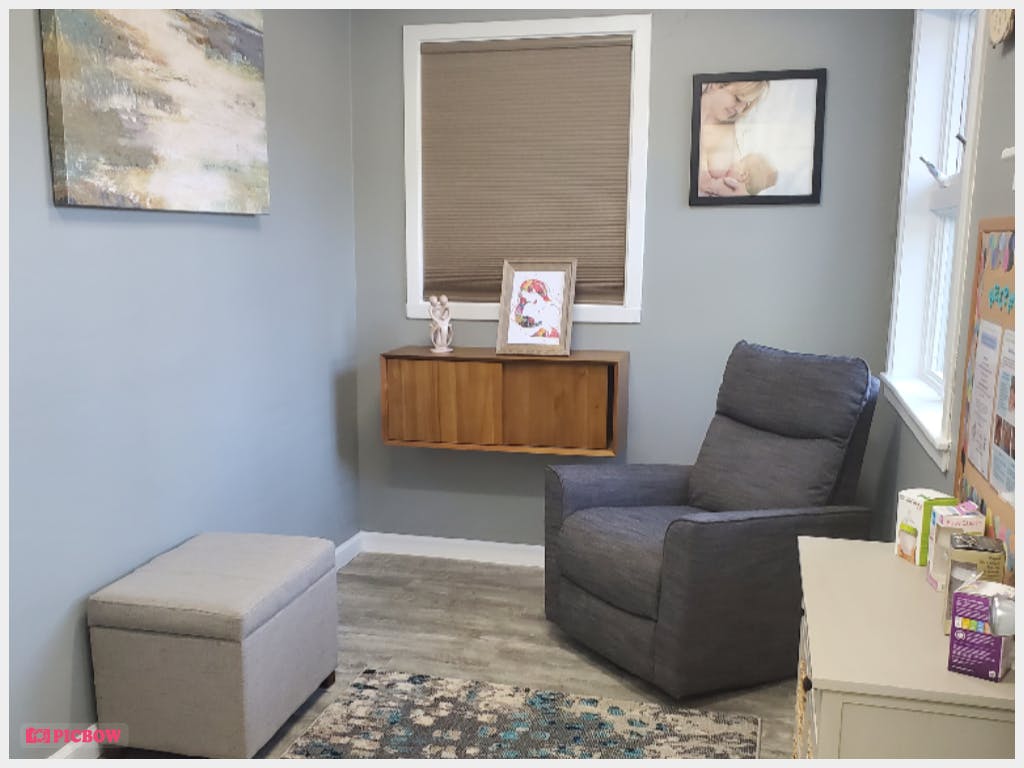 Room with a gray recliner, ottoman, and floating wooden cabinet