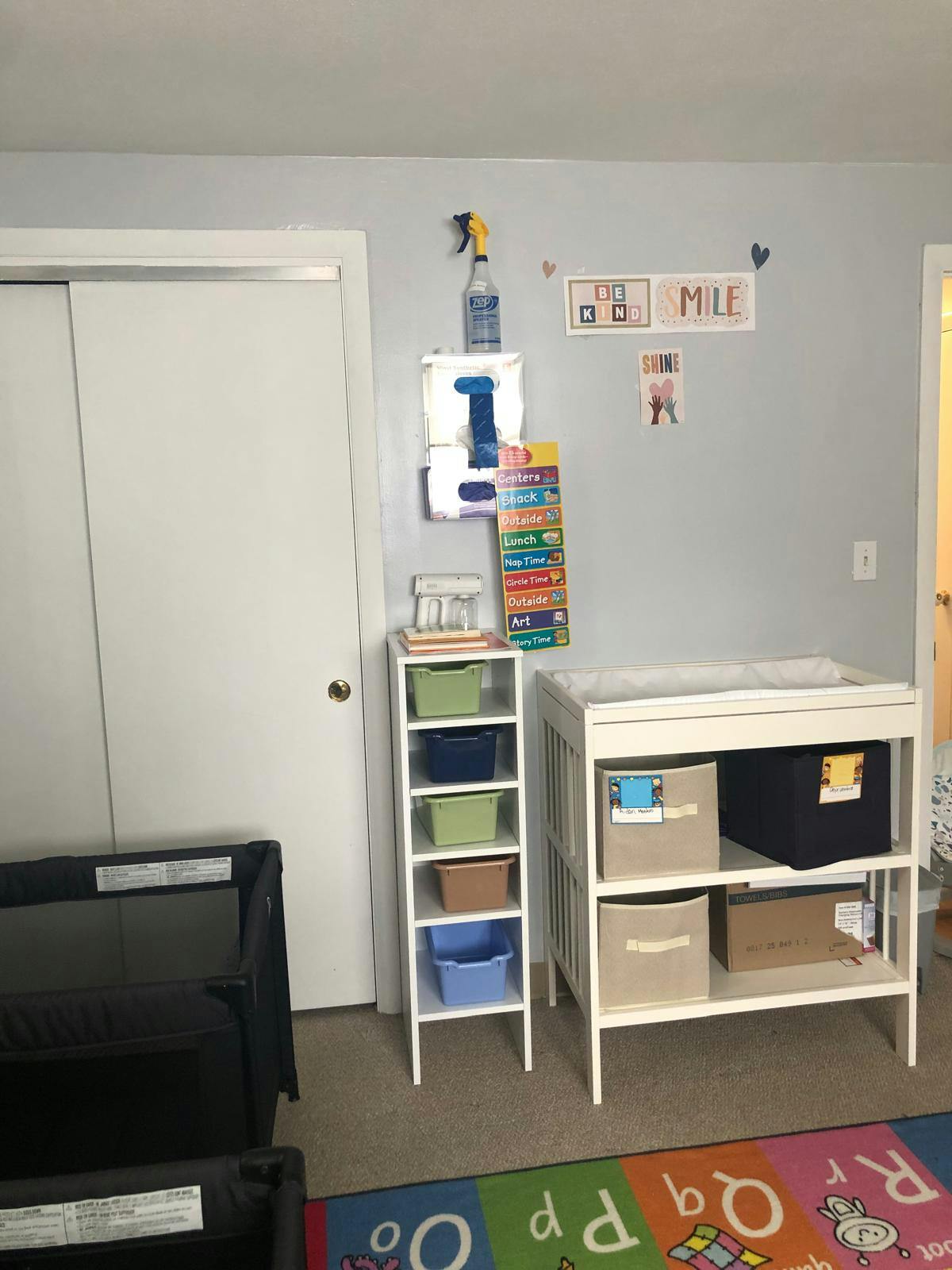 child care room with two cribs, changing table, and shelving with daily schedule