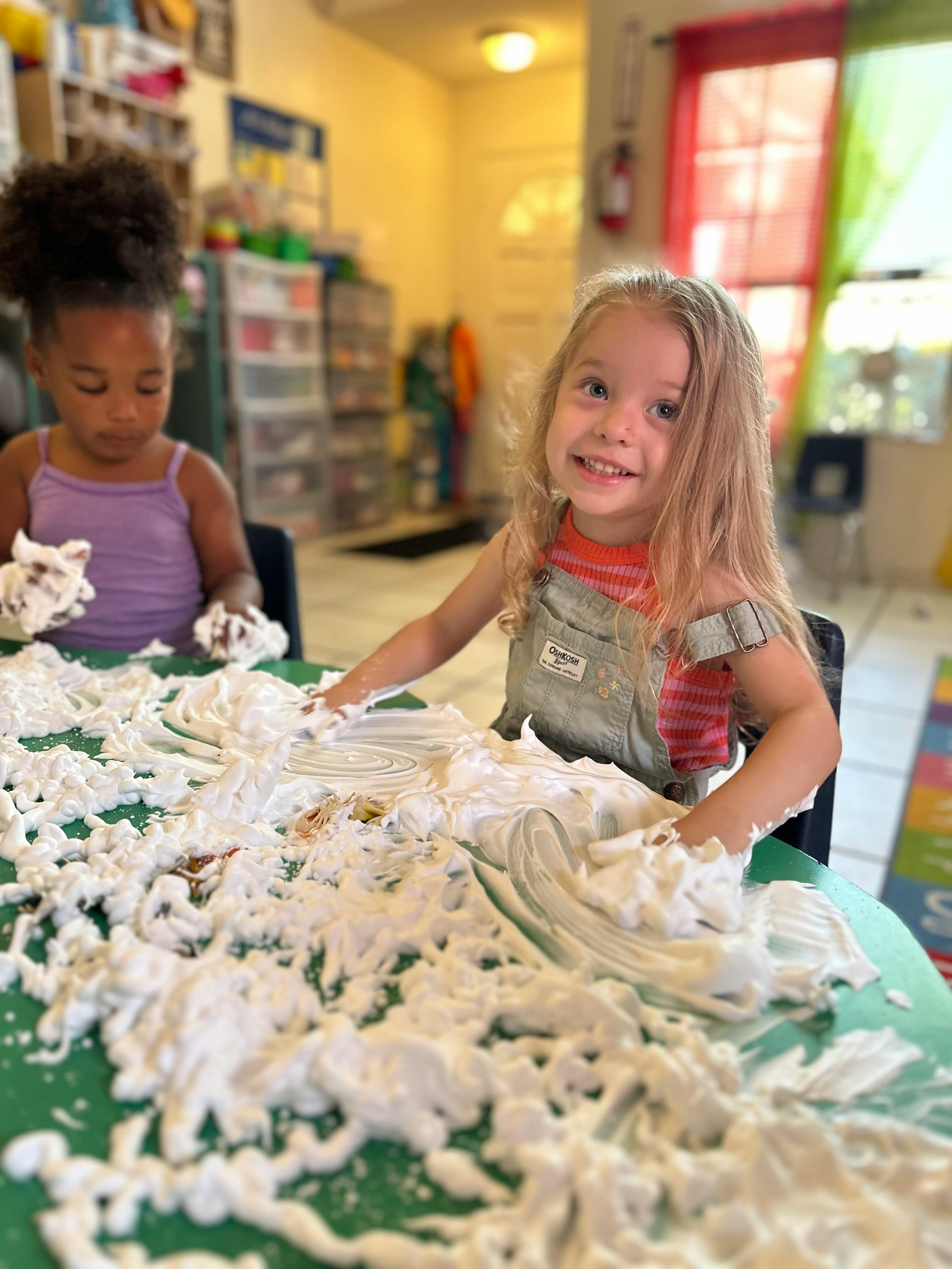 Two children playing with shaving cream on a table