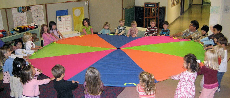 Children and adults holding a colorful parachute