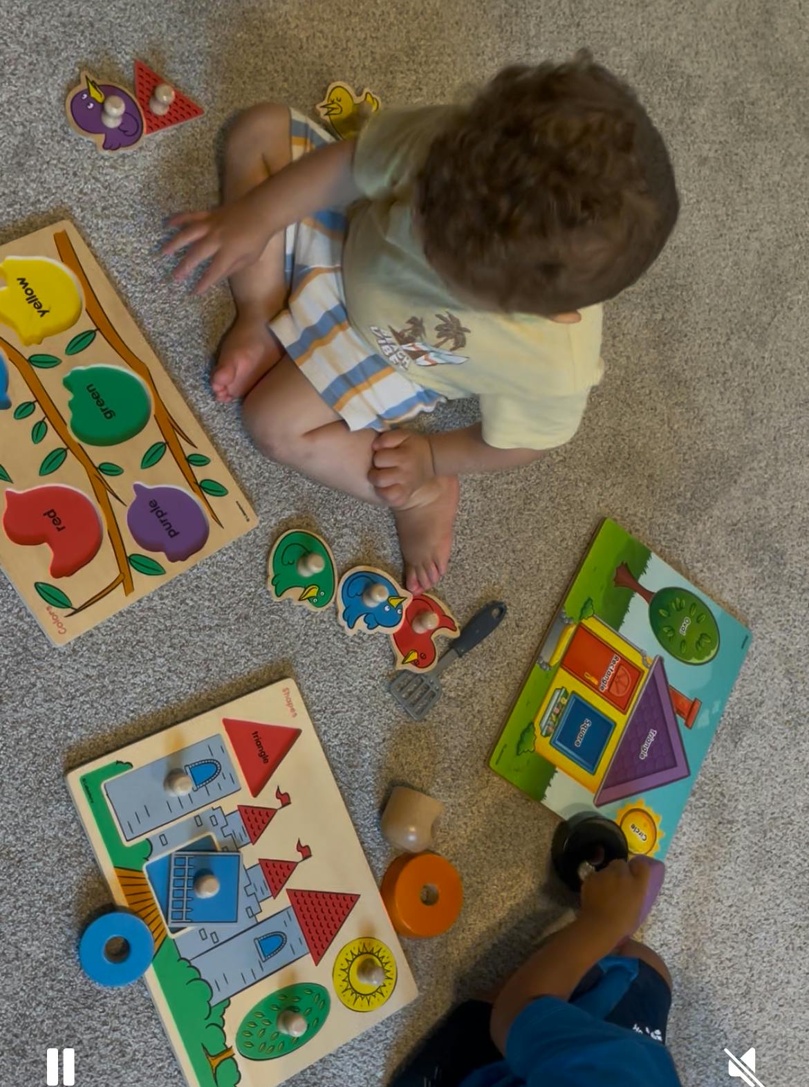 Child sitting on a carpet playing with colorful educational shape puzzles