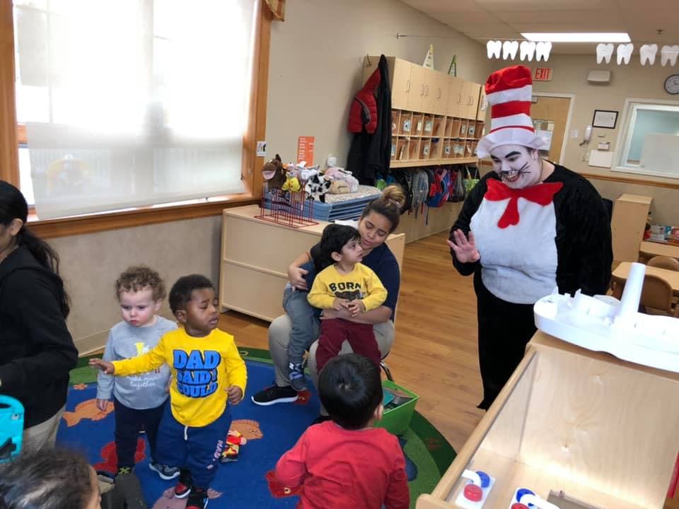 Person in Cat in the Hat costume interacting with children in a classroom