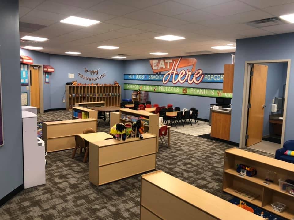 Classroom with tables, chairs, and a wall sign that says "Eat Here"