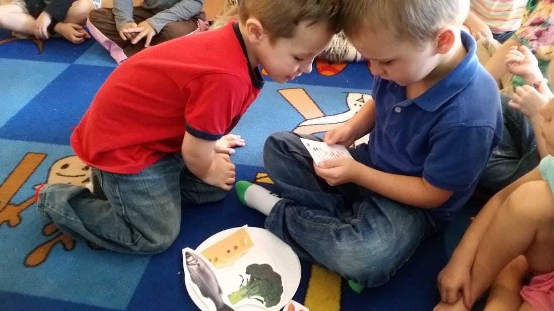 Two children looking at a small card on a patterned rug