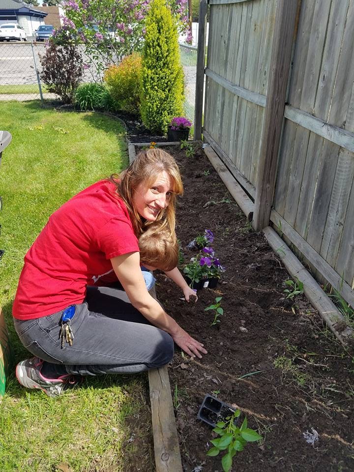 Person and child planting flowers in a garden