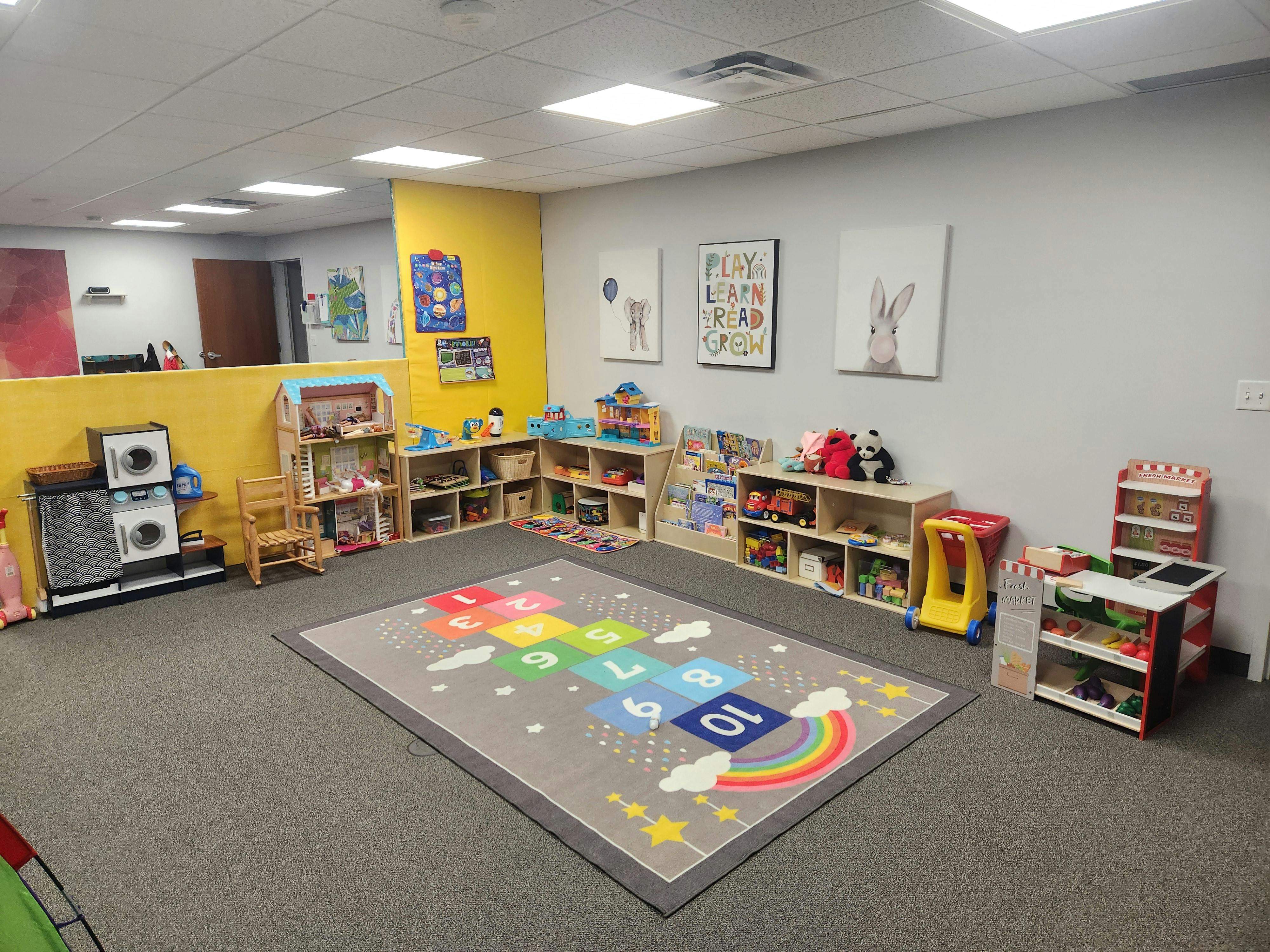 Playroom with a hopscotch rug and shelves of toys