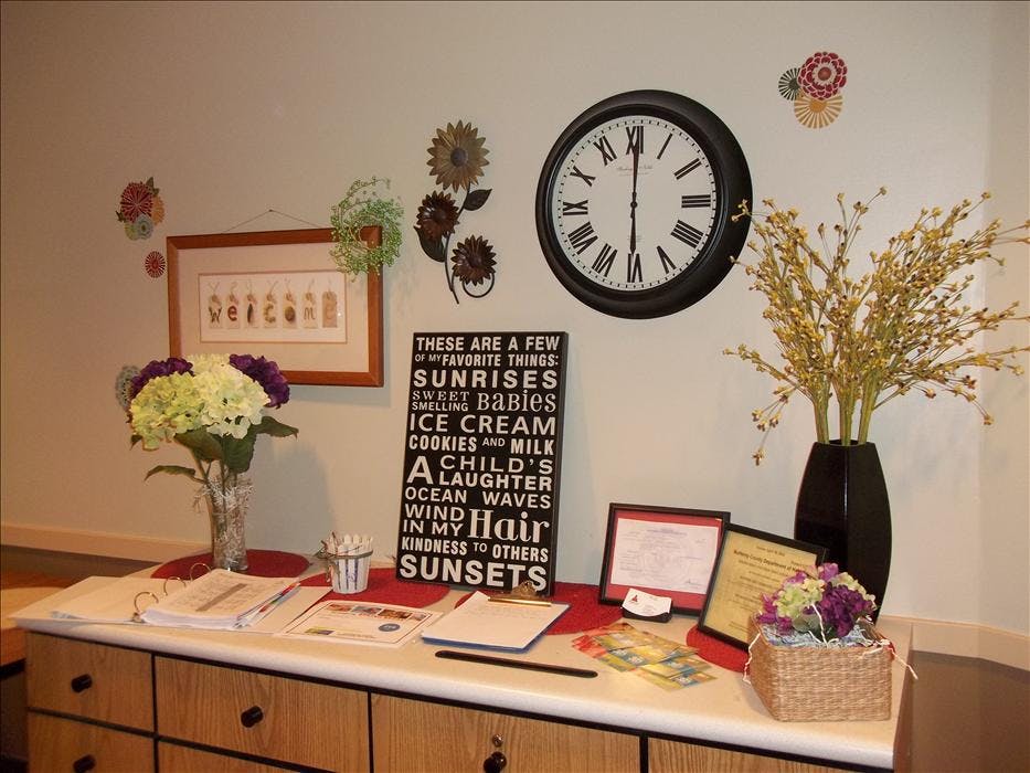 Reception desk with welcome sign, flowers, clock, and a sign listing "favorite things"