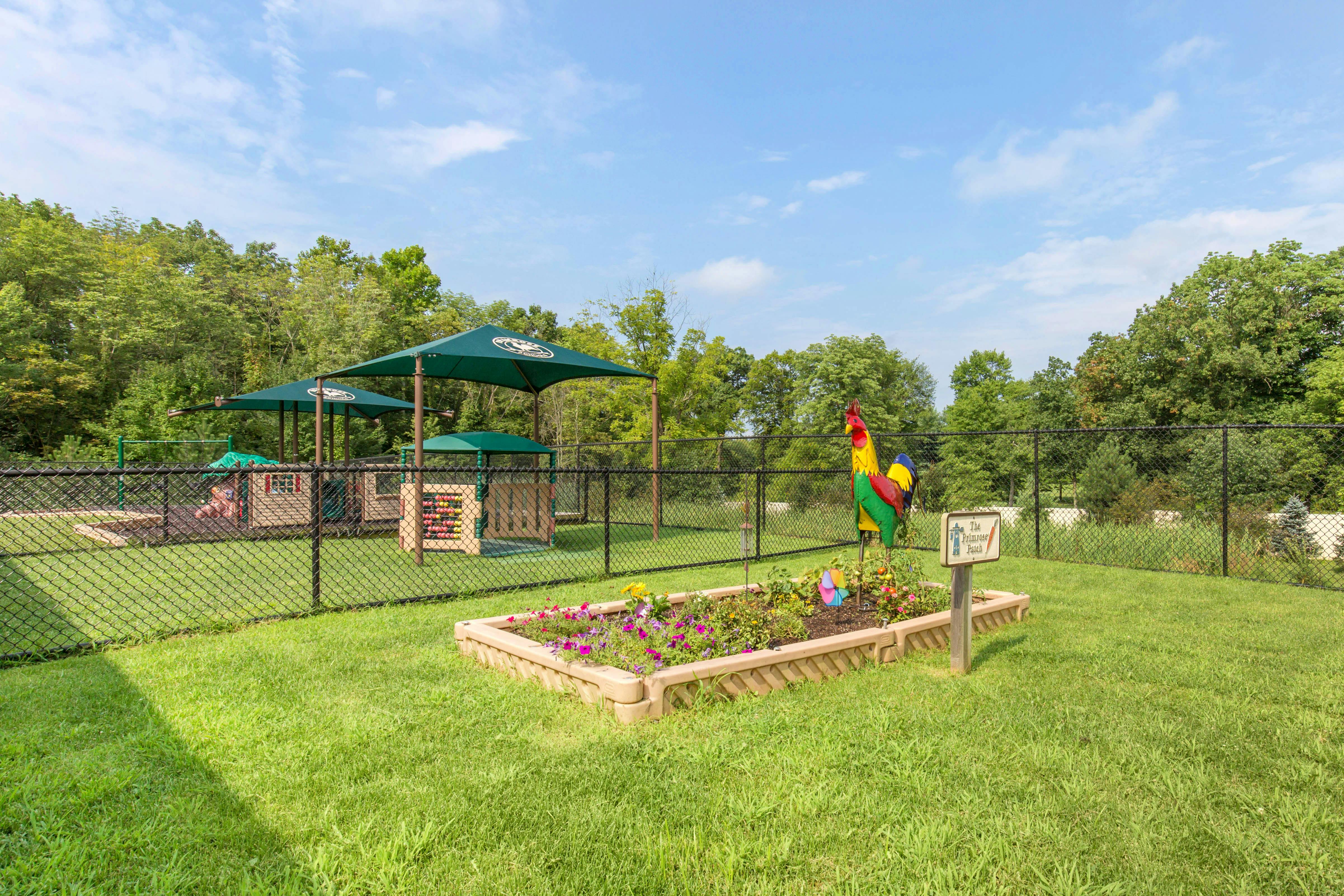 A fenced playground area with green canopies and a wooden playhouse