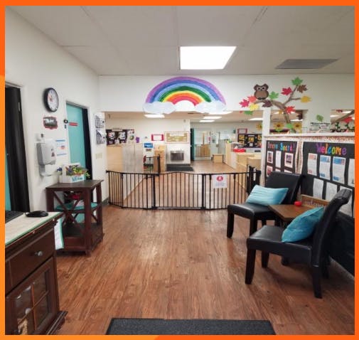 Childcare center hallway with a rainbow decoration, chairs, and a safety gate